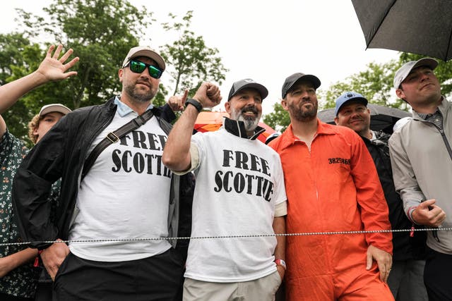 <p>Spectators wore ‘Free Scottie’ t-shirts and one wore an orange jumpsuit, like that shown in the mugshot of Scottie Scheffler on Friday </p>