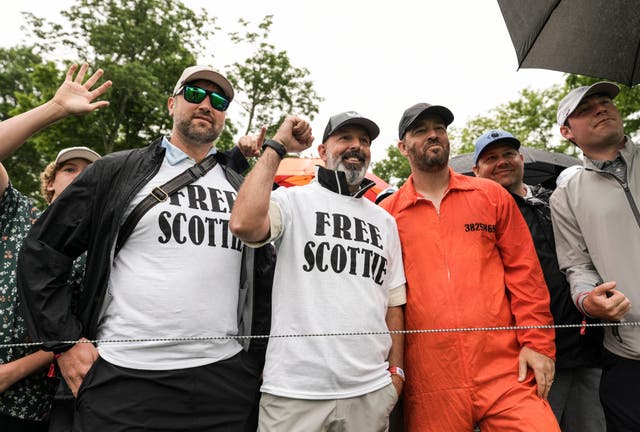 <p>Spectators wore ‘Free Scottie’ t-shirts and one wore an orange jumpsuit, like that shown in the mugshot of Scottie Scheffler on Friday </p>