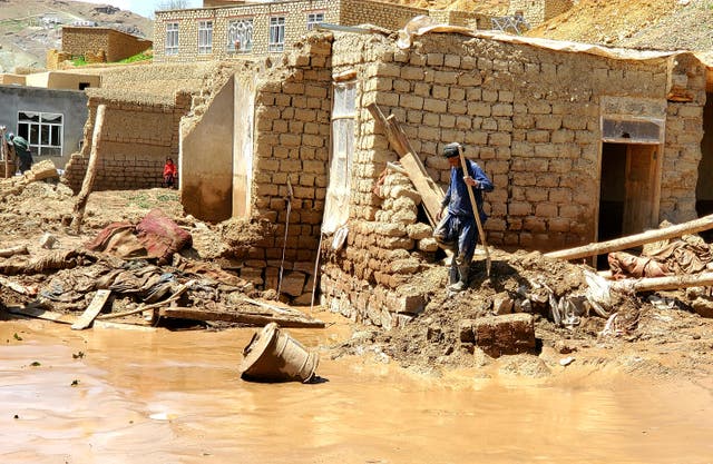 <p>An Afghan man collects his belongings from his damaged home after heavy flooding in Ghor province in western Afghanistan, Saturday, 18 May 2024</p>