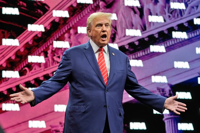 <p>Former President Donald Trump gestures as he is applauded before speaking at the National Rifle Association Convention on 18 May 2024</p>