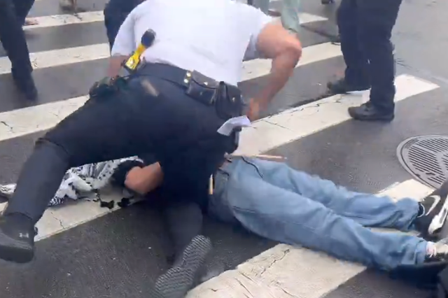 <p>A New York Police Department officer pictured punching an anti-war demonstrator during a protest in Brooklyn on 18 March</p>