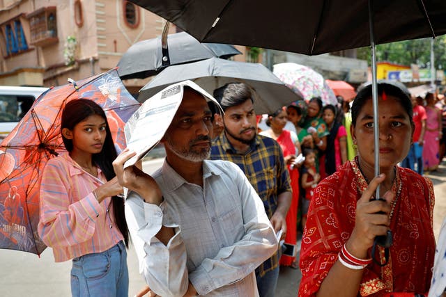 <p>People use umbrellas and newspapers to beat the heat as they wait to vote in West Bengal on 20 May 2024</p>