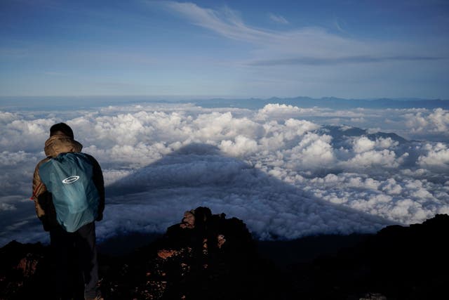 <p> The shadow of Mount Fuji is casted on clouds hanging below the summit</p>