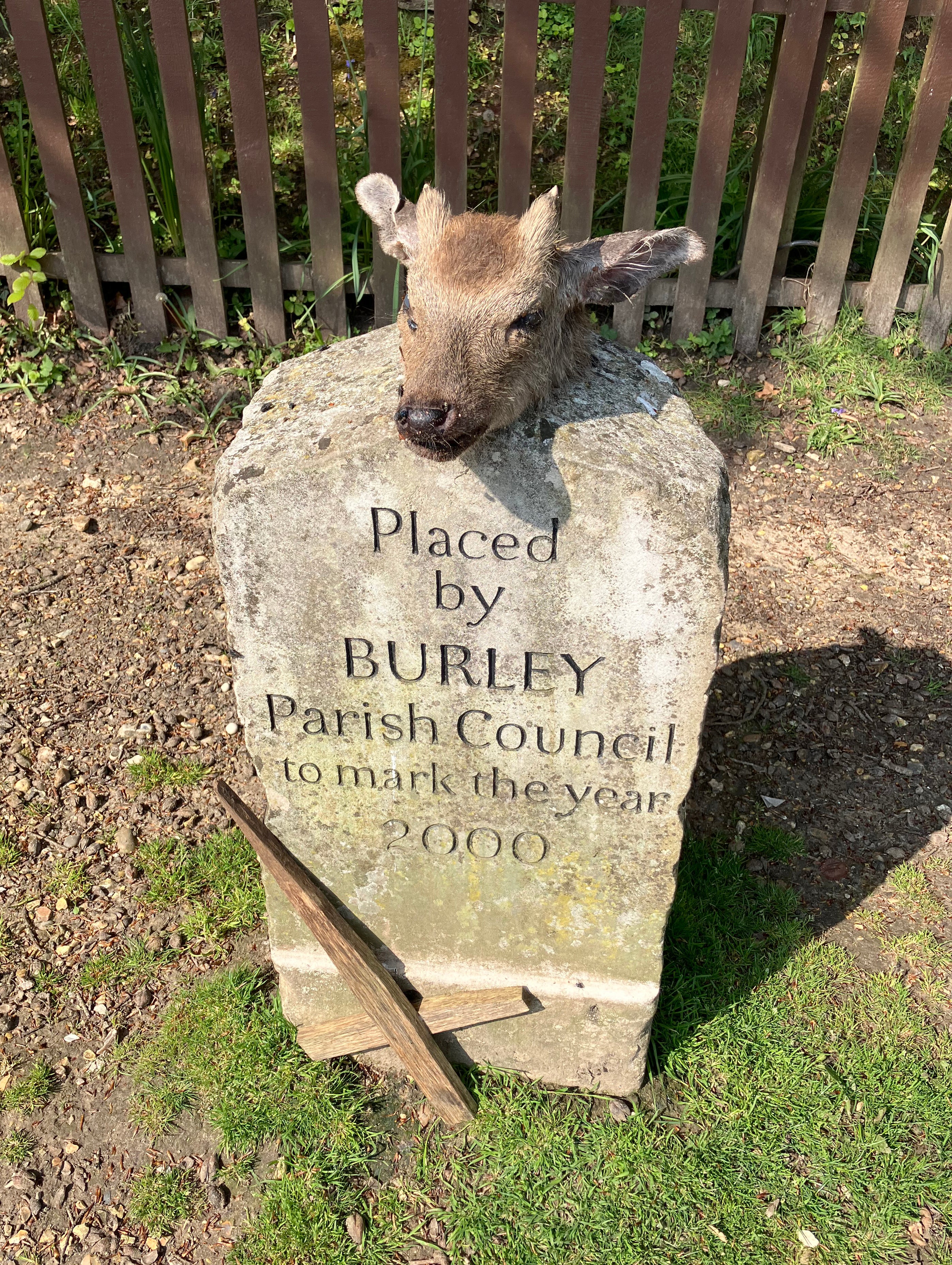 The deer head on a New Forest memorial stone and an upside down cross place next to it in Burley village
