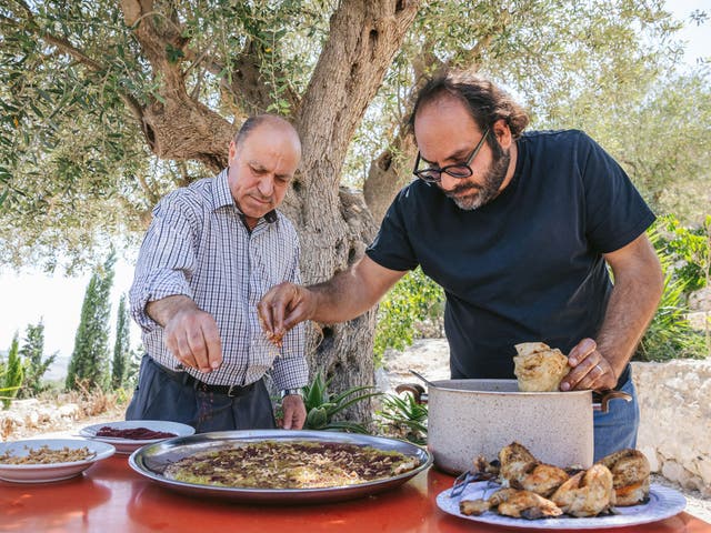 <p>Kattan, right, making the Palestinian dish musakhan with restaurant owner Abu Mohammad</p>