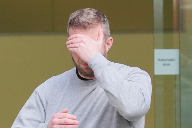 <p>Matthew Trickett covering his face as he left Westminster Magistrates' Court, central London, after appearing in court accused of assisting the Hong Kong intelligence service</p>