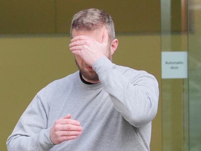 <p>Matthew Trickett covering his face as he left Westminster Magistrates' Court, central London, after appearing in court accused of assisting the Hong Kong intelligence service</p>