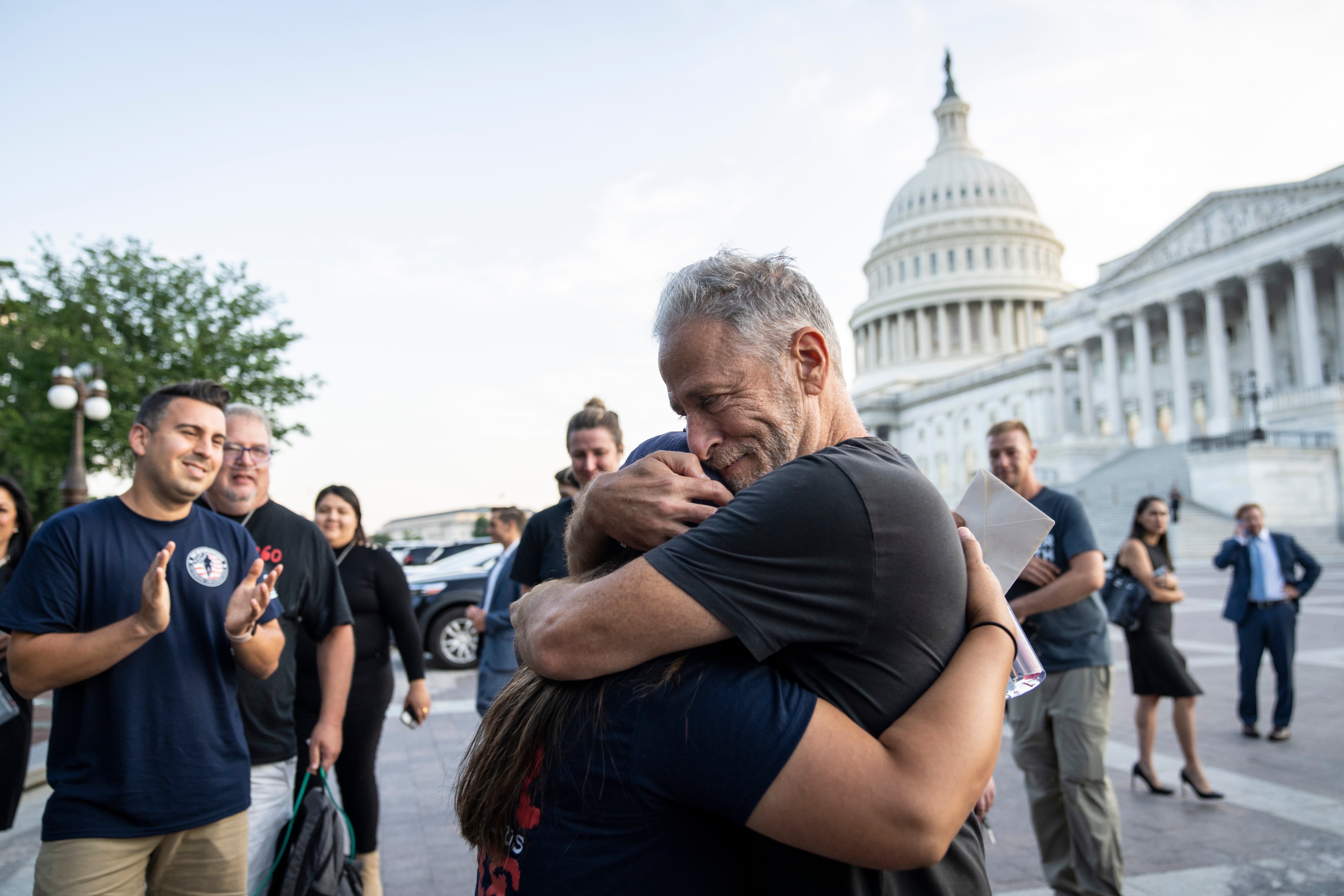Comedian and activist Jon Stewart hugs Rosie Torres, wife of veteran Le Roy Torres who suffers from illnesses related to his exposure to burn pits in Iraq, after the Senate passed the PACT Act at the US Capitol August 2, 2022