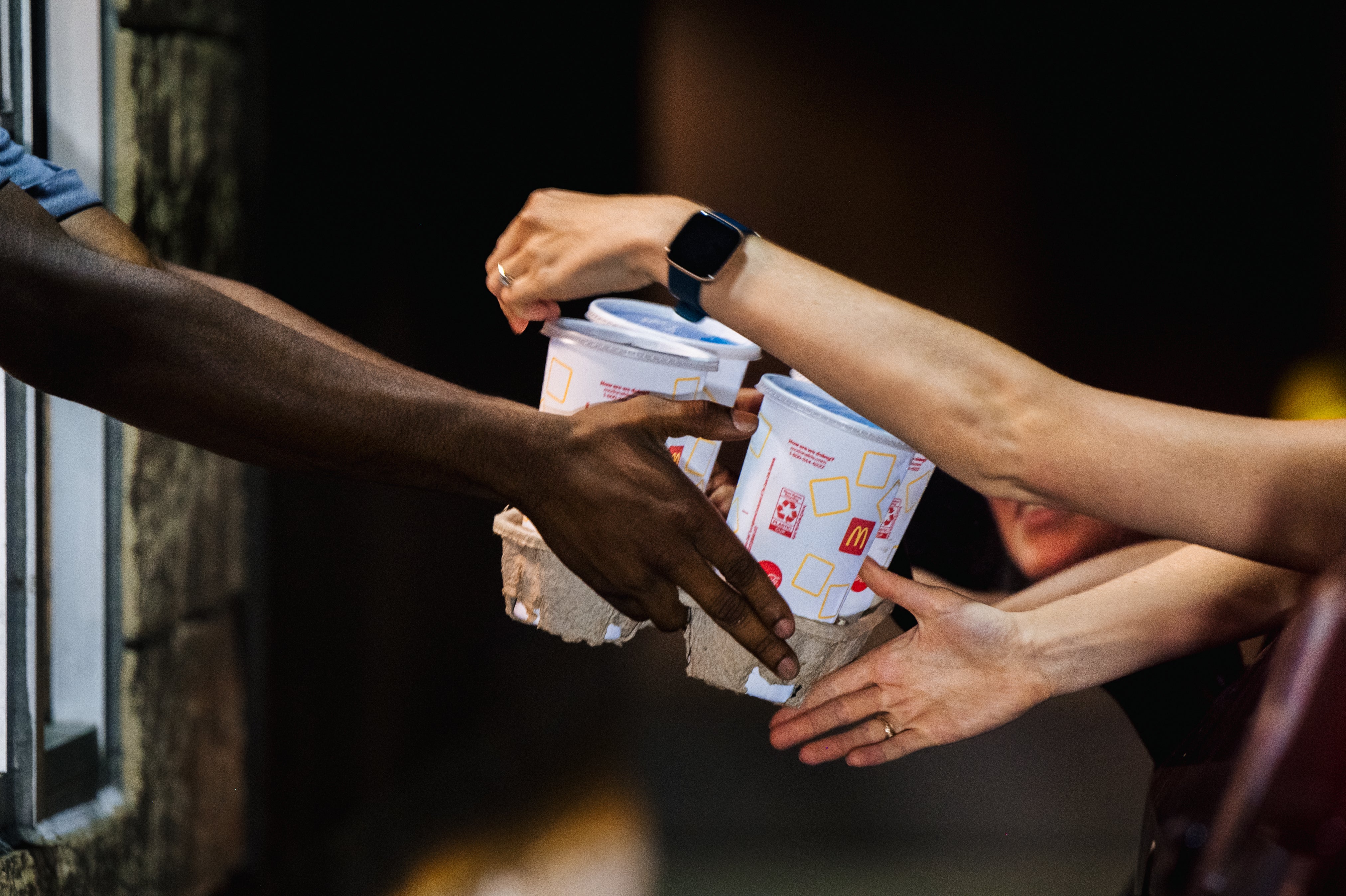 A McDonald’s employee hands a customer drinks. Individual franchisees may choose to eliminate free refills, the company said