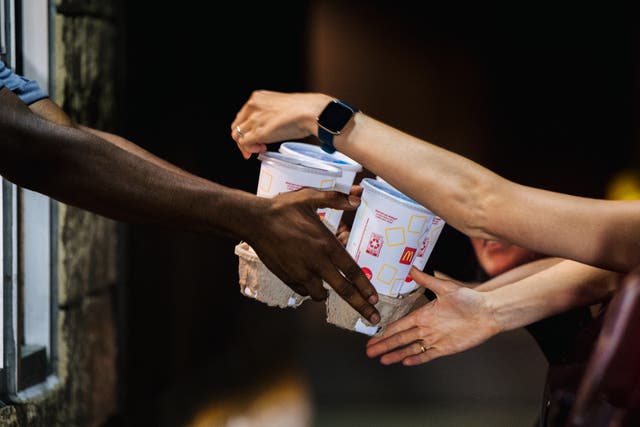 <p>A McDonald’s employee hands a customer drinks. Individual franchises may choose to eliminate free refills, the company said</p>