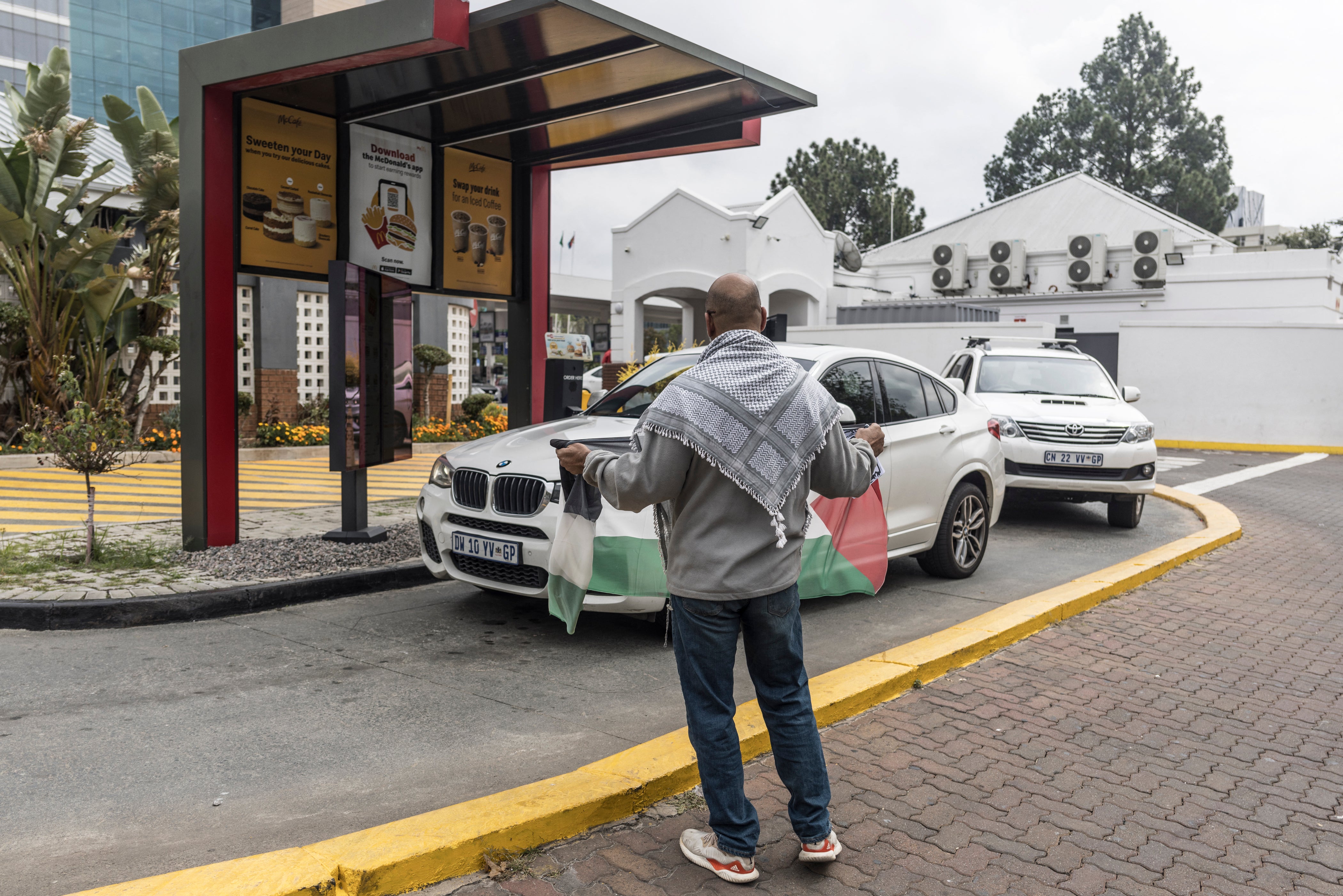 A pro-Palestine protester holds a Palestinian flag in a McDonald’s drive-thru. McDonald’s recently bought back all 225 franchise locations in Israel in response to the boycotts