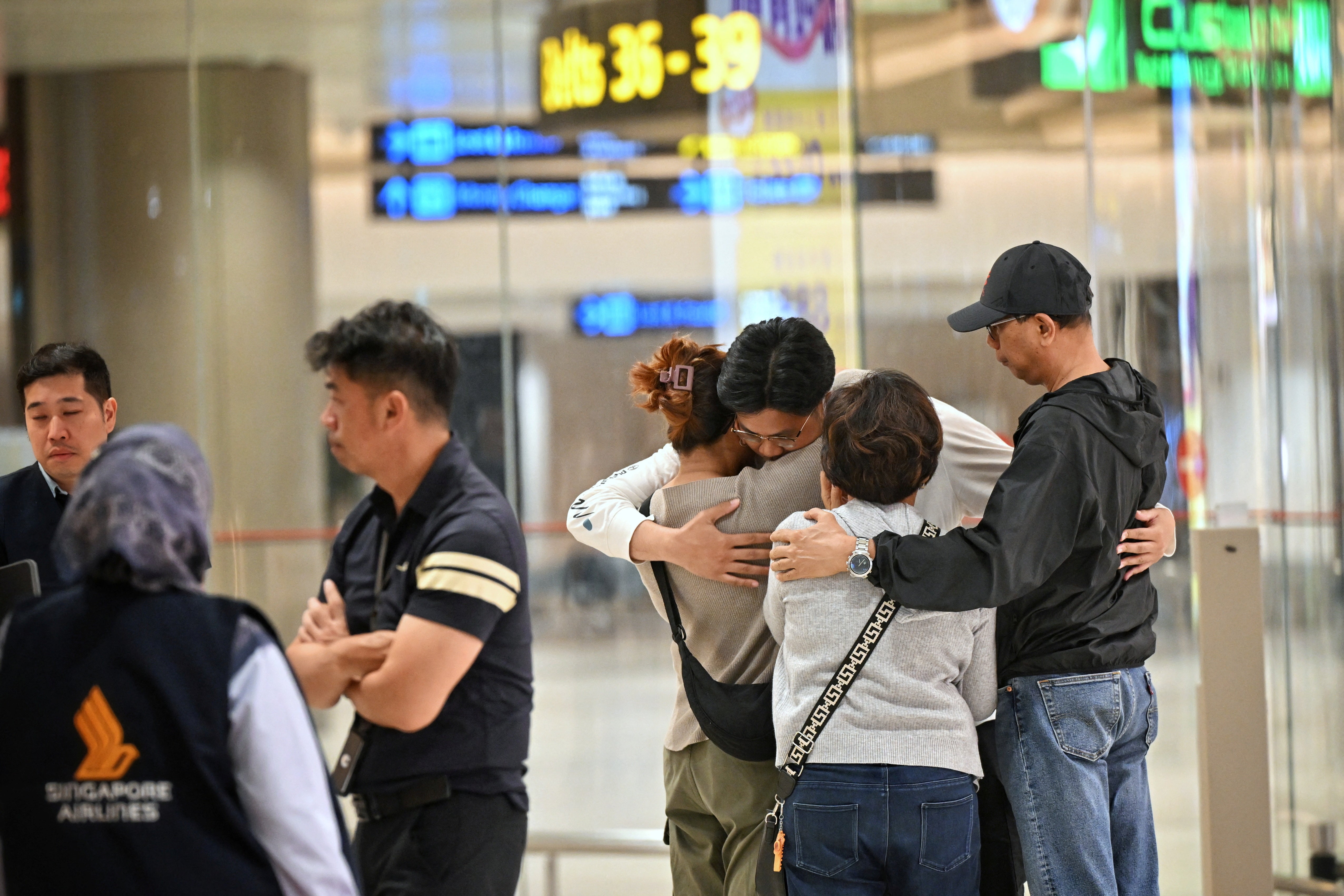 Passengers who experienced severe turbulence on a Singapore Airlines flight embrace after landing in Singapore