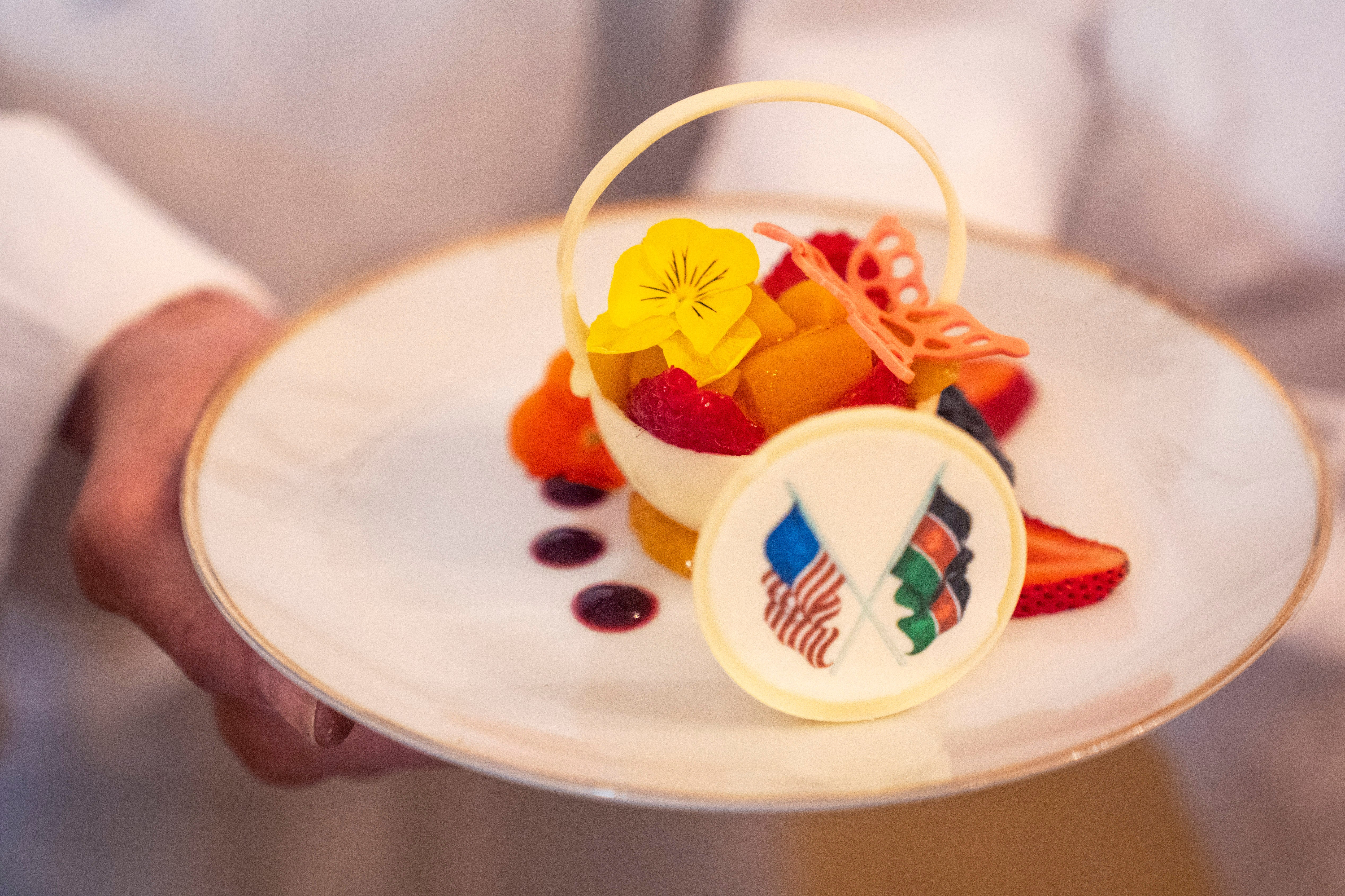 White House Executive Pastry Chef Susie Morrison holds a dessert of a white chocolate basket with banana ganache, raspberries, peaches, and candied lime zest