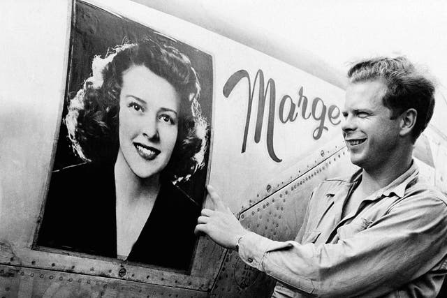 <p>Captain Richard Bong points to a large picture of his girl friend, Marge Vattendahl, on his Lighting P-38 fighter plane pilot stationed at a New Guinea Air Base, March 31, 1944</p>