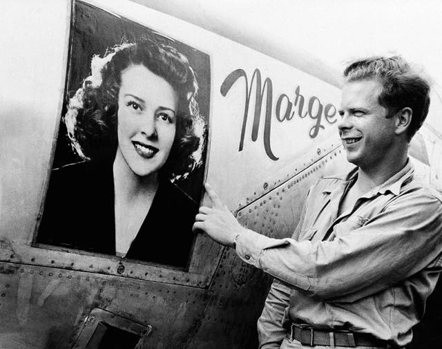 <p>Captain Richard Bong points to a large picture of his girl friend, Marge Vattendahl, on his Lighting P-38 fighter plane pilot stationed at a New Guinea Air Base, March 31, 1944</p>