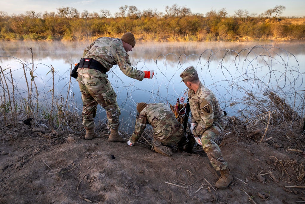 Two members of the Texas National Guard install razor wire along the US-Mexico border in Eagle Pass, Texas