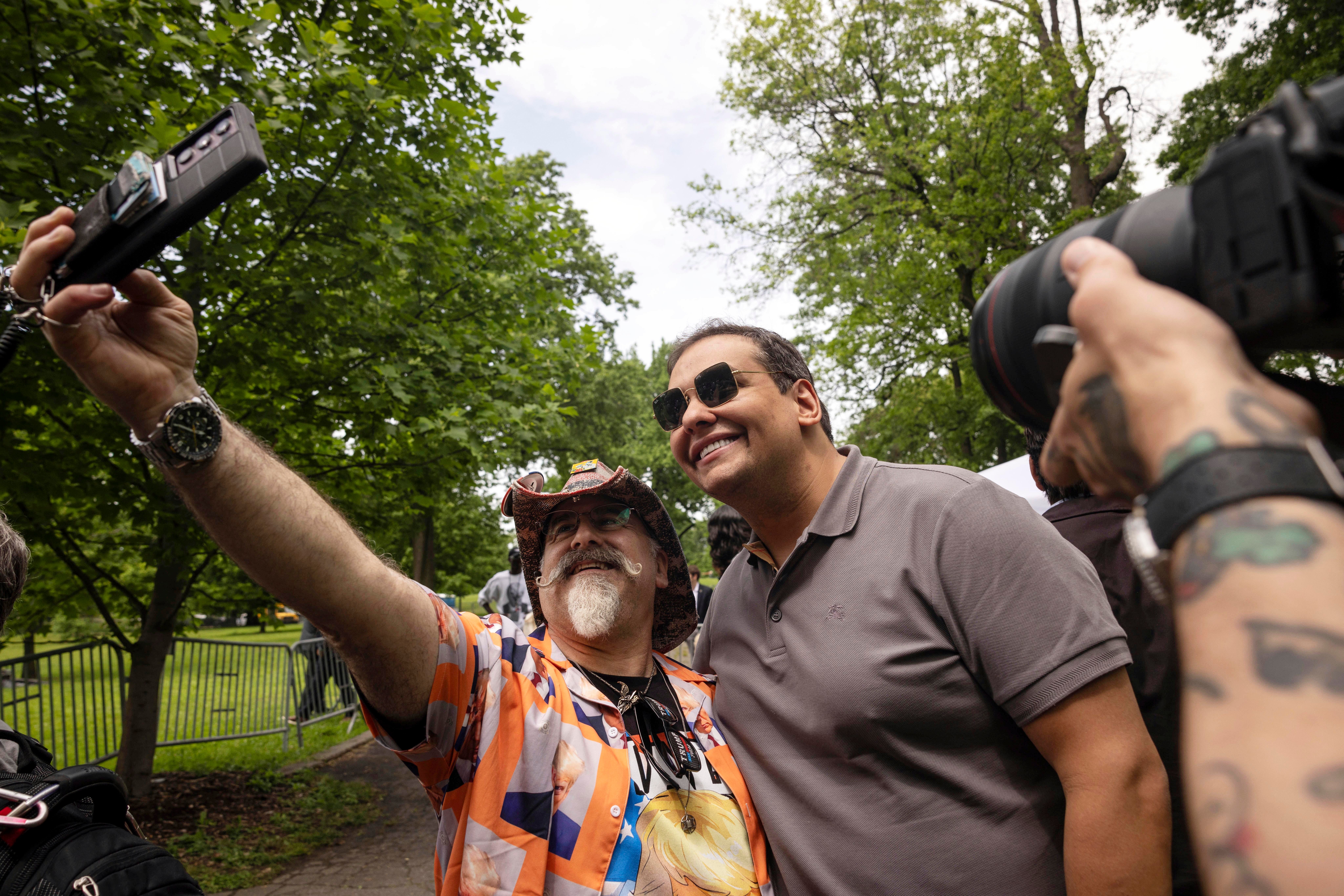 Former Rep George Santos (aka Kitara Ravache), right, takes pictures with supporters outside the Trump campaign rally in the South Bronx