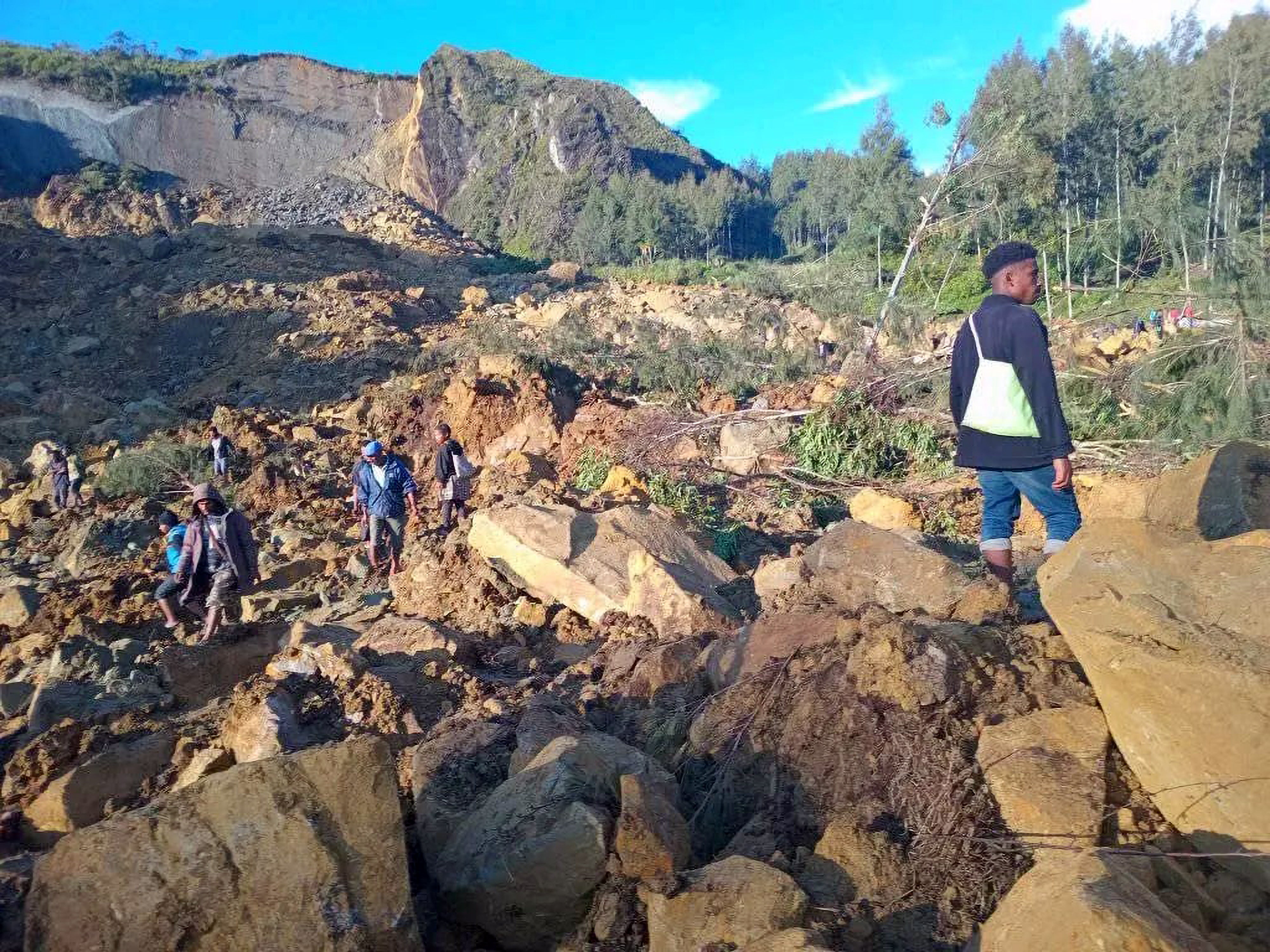People walk with their belongings in the area where a landslide hit the village of Kaokalam, Enga province, Papua New Guinea