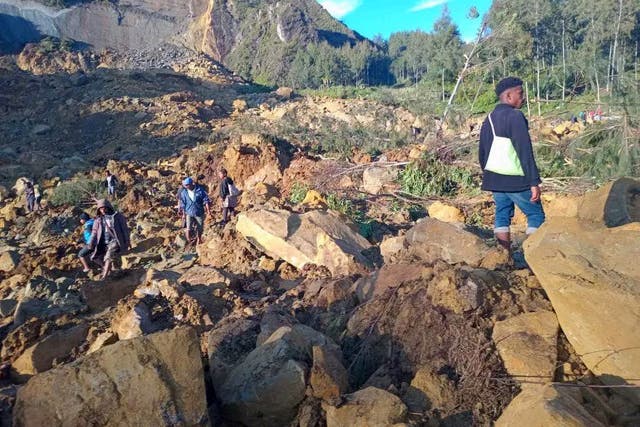 <p>People walk with their belongings in the area where a landslide hit the village of Kaokalam, Enga province, Papua New Guinea</p>