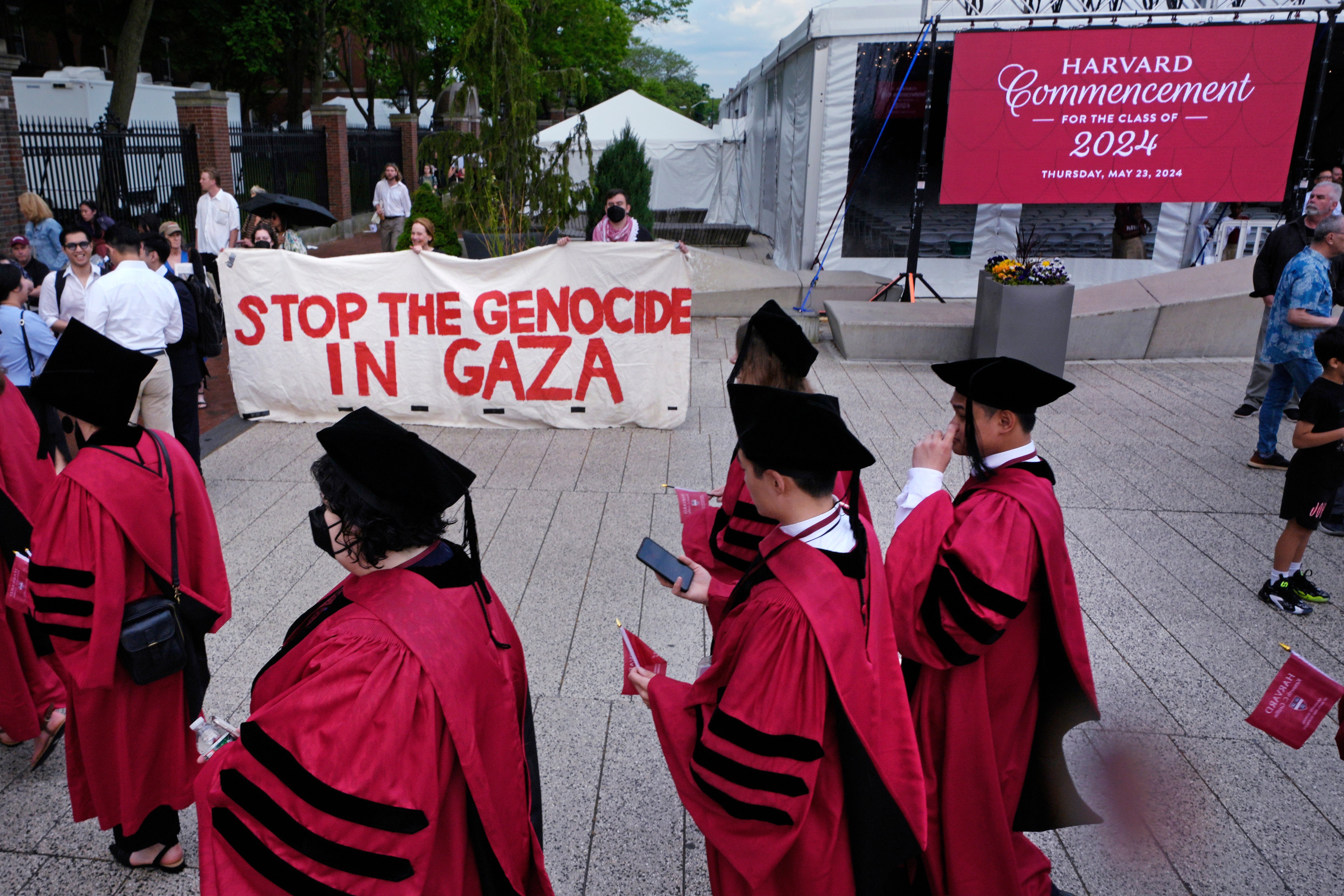 Harvard University students pass protestors while making their way into Harvard Yard for commencement on Thursday