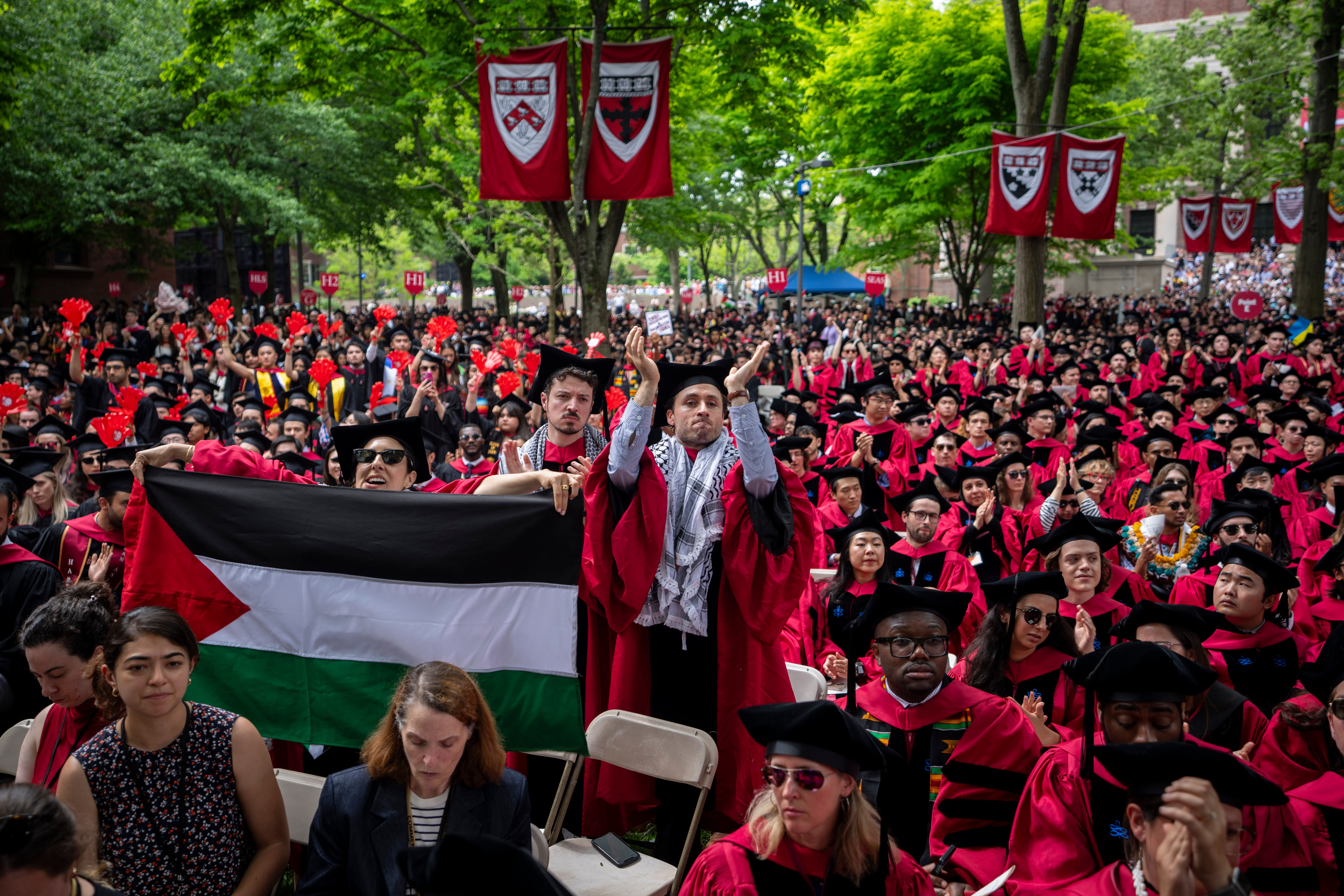 Students graduating hold up a Palestinian flag duirng the graduation ceremony in Harvard Yard, at Harvard University on Thursday