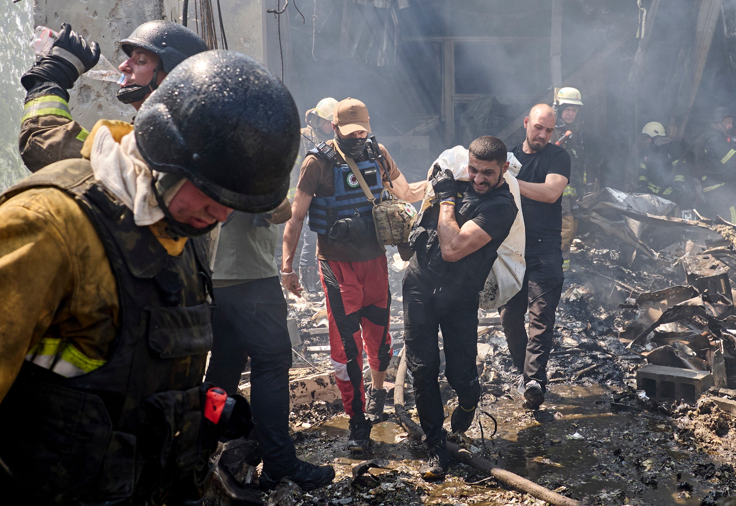 Rescuers carry the body of a victim at the site of a shelling on a printing house in Kharkiv