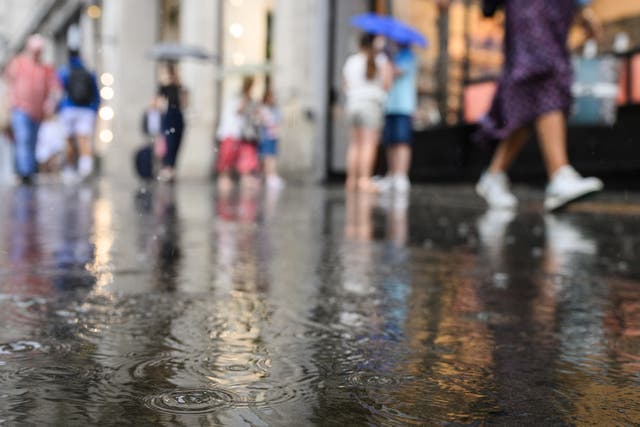 <p>Raindrops land in a puddle as shoppers rush through a heavy downpour on August 16, 2022 in London, England</p>