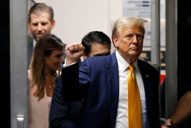 <p>Former US President Donald Trump raises his fist as he walks to the courtroom following a break in his trial for allegedly covering up hush money payments linked to extramarital affairs, at Manhattan Criminal Court in New York City, on 14 May 2024</p>
