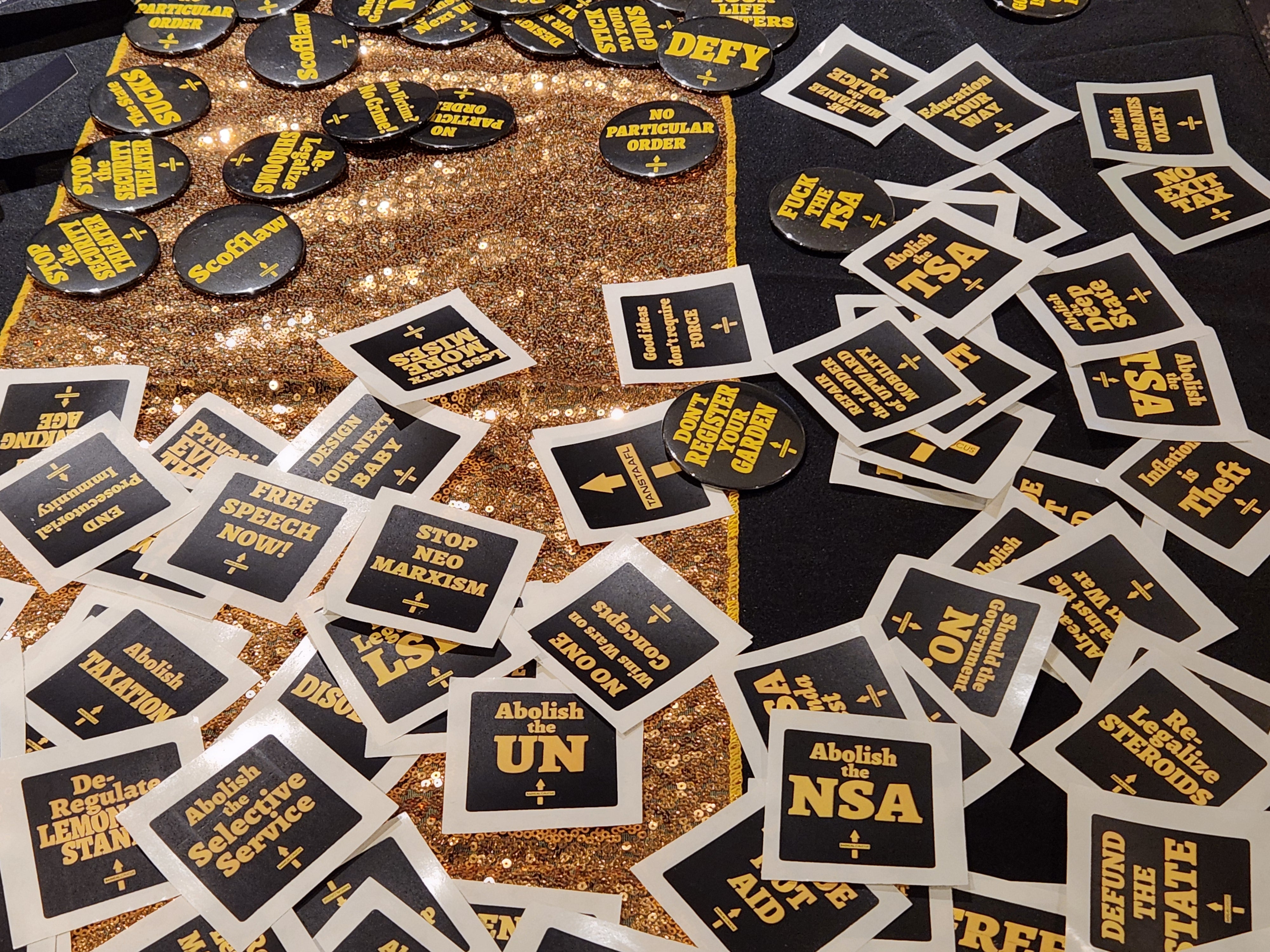 Buttons and stickers with federal-skeptic slogans are handed out at the 2024 Libertarian Party convention in Washington DC