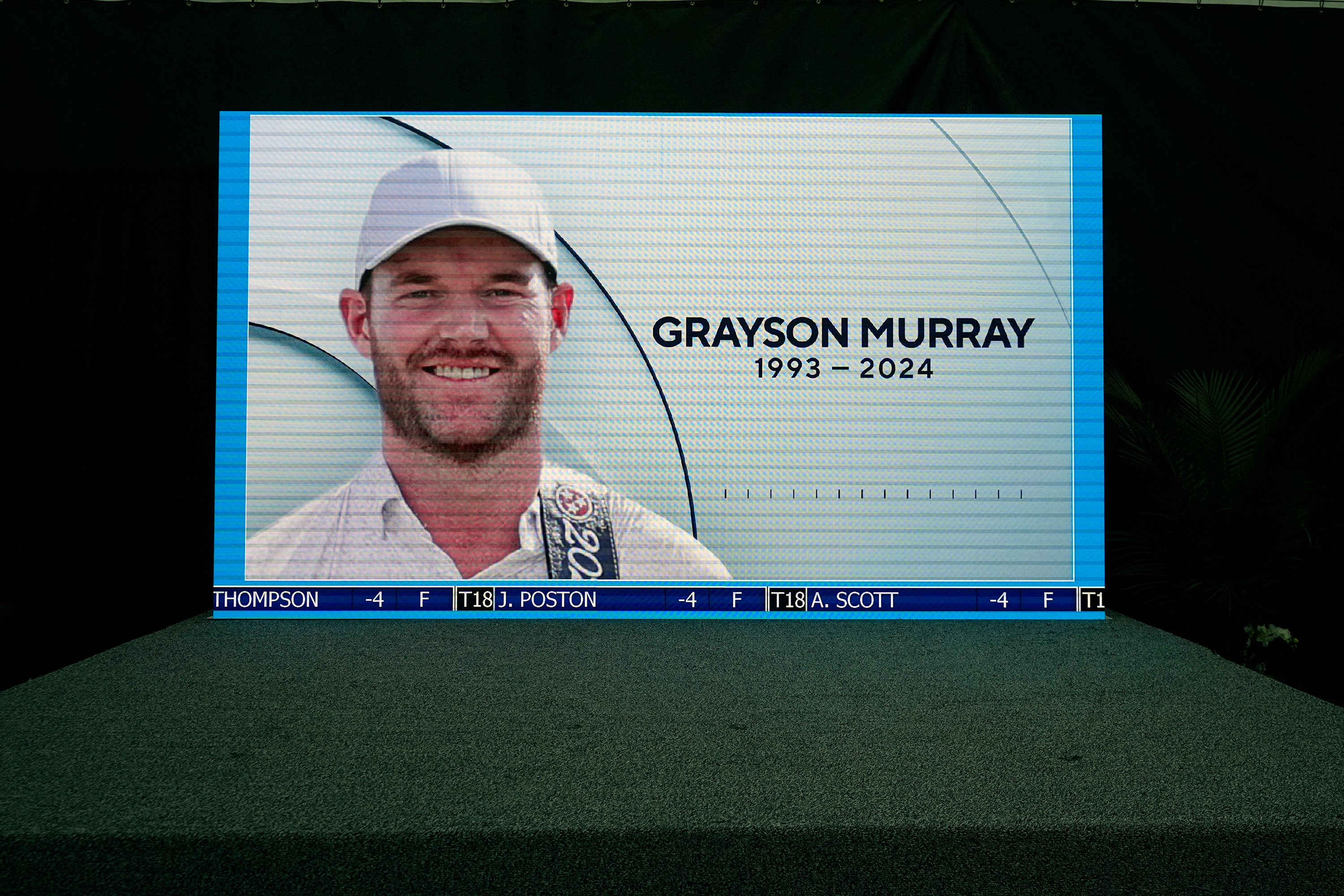 A golf broadcast by CBS is played on an empty stage at the media center showing a photo of Grayson Murray