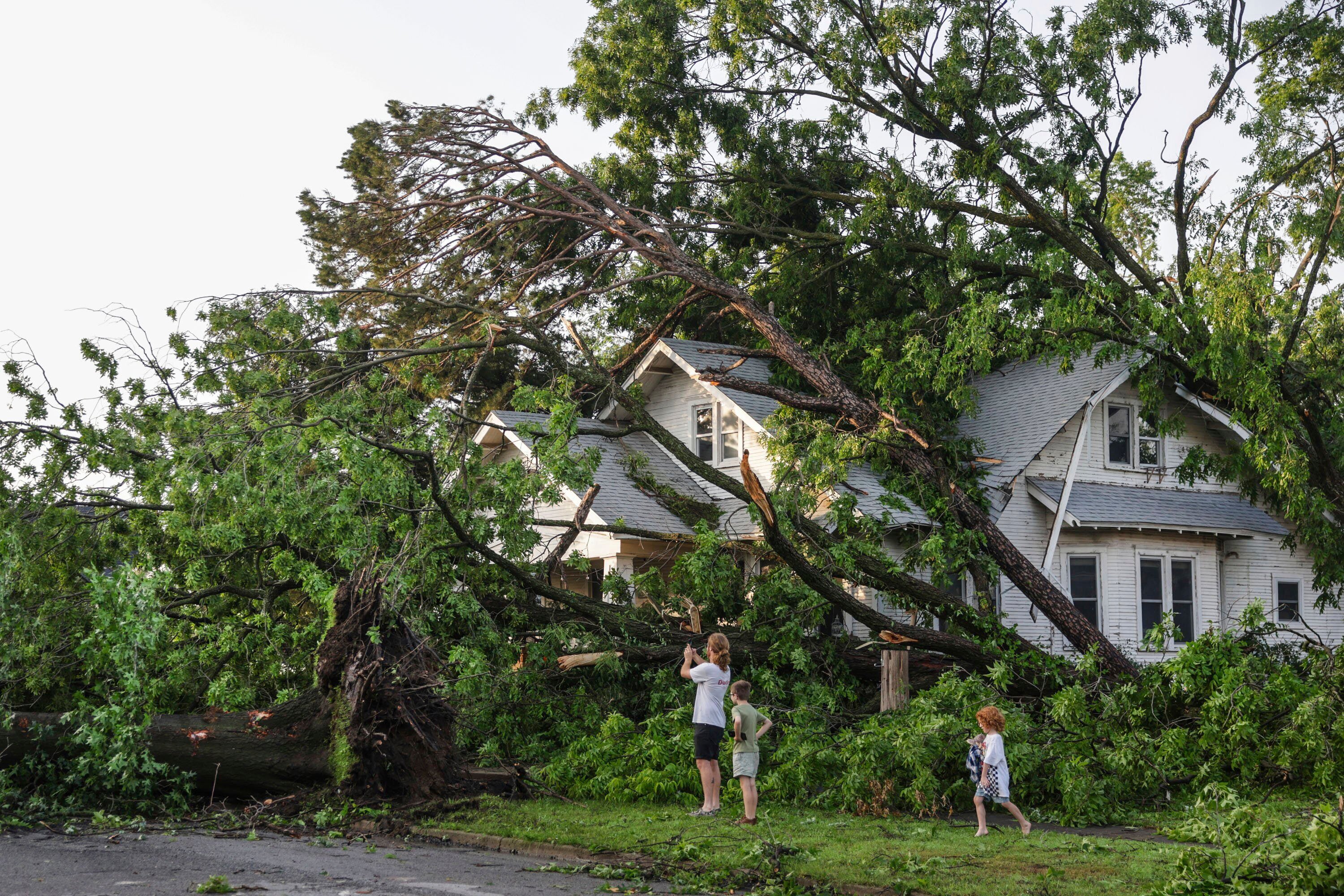 Max Comer and his sons, Finnegan, 9, and McCoy, 5, view storm damage to their next door neighbor's home, Sunday, May 26, 2024, in Claremore, Okla