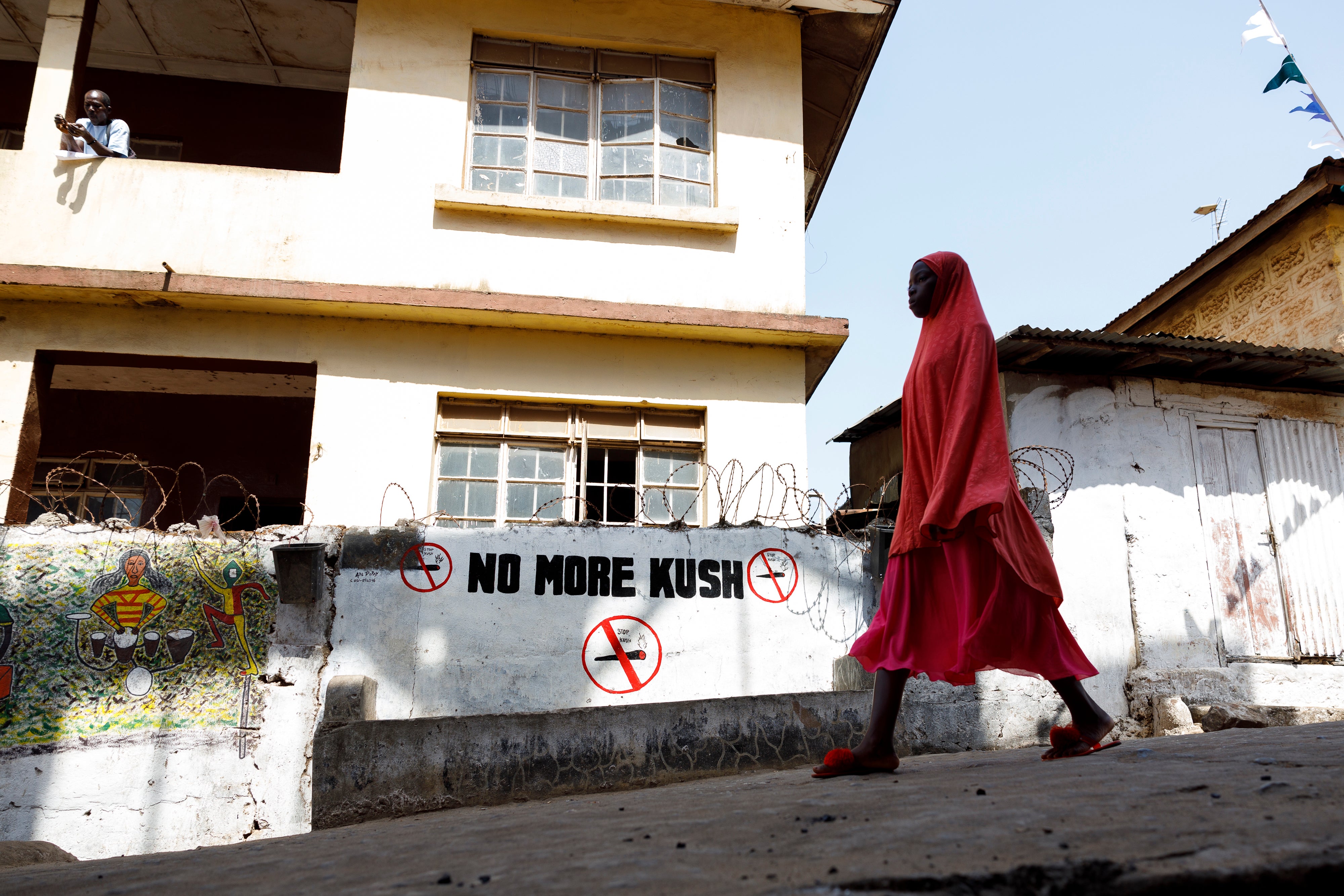 A girl walks past a ‘No more Kush’ warning on a wall on Bombay Street in Freetown, Sierra Leone