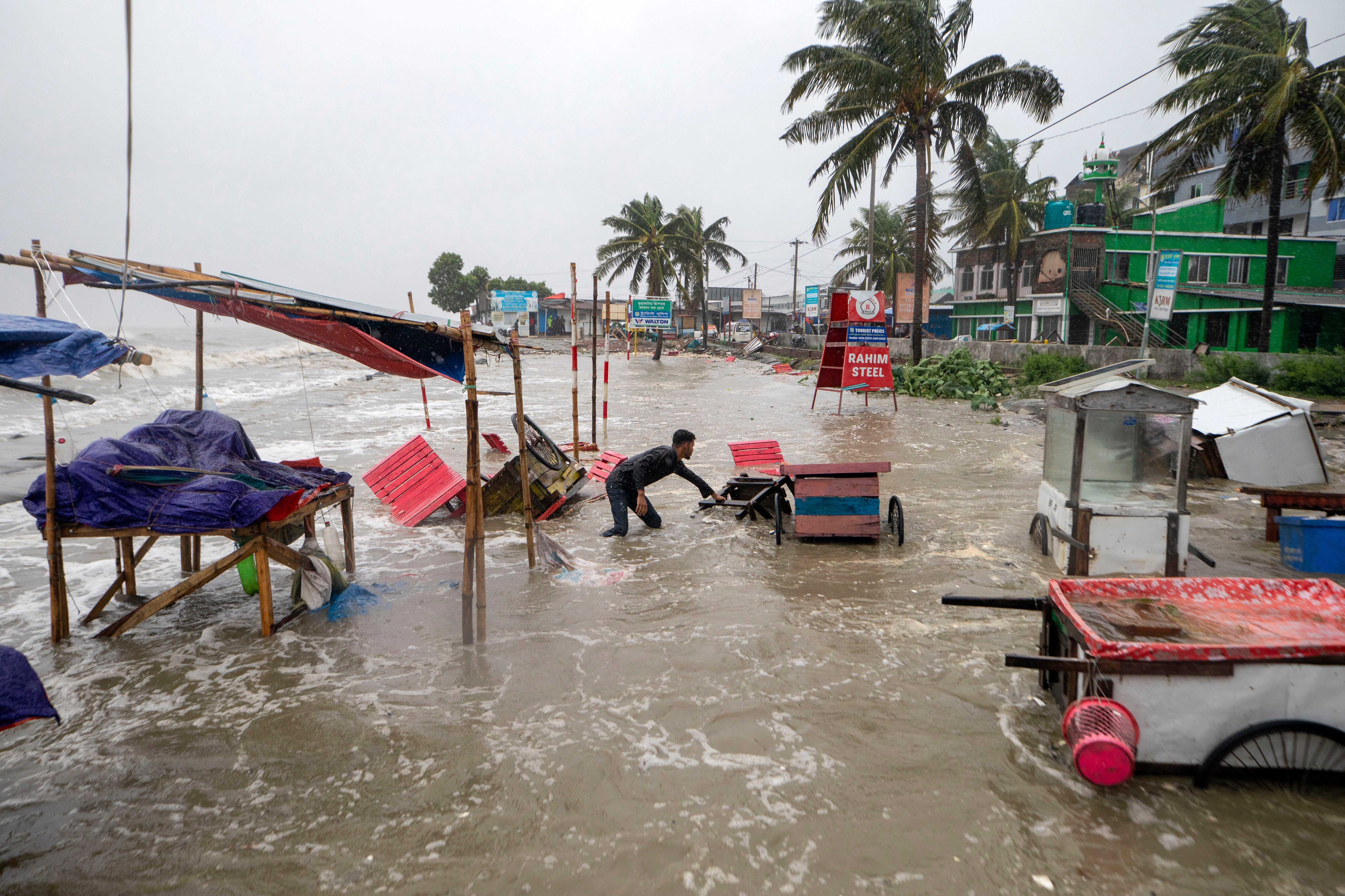 A man salvages a cart and other material as water flows on to the Kuakata beach on the coast of Bay of Bengal caused by the advancing Cyclone Remal in Barisal, Bangladesh, Sunday, 26 May 2024