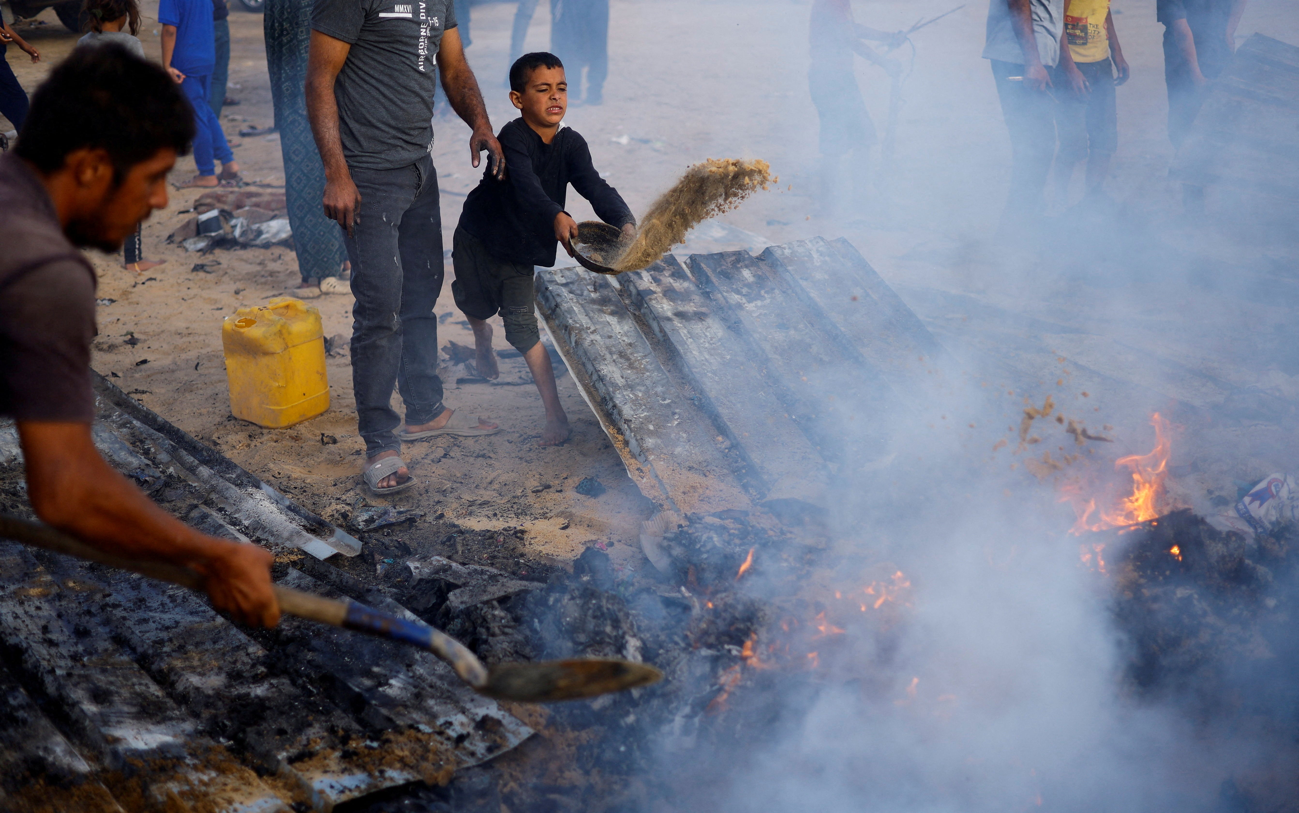 Palestinians put out a fire at the site of an Israeli strike on an area designated for displaced people in Rafah