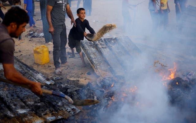<p>Palestinians put out a fire at the site of an Israeli airstrike on an area designated for displaced people in Rafah </p>