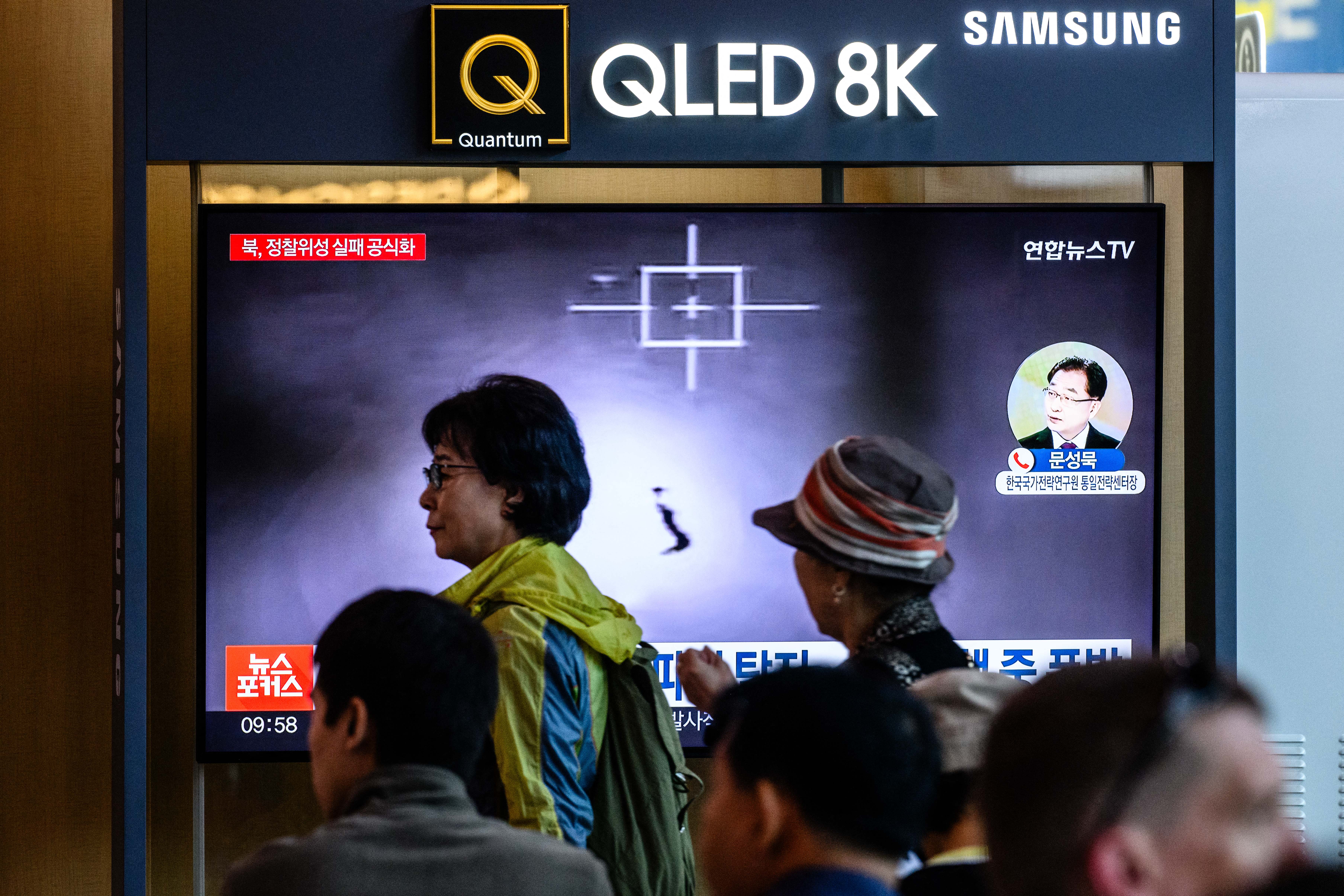 People walk past a TV showing the launch at a train station in Seoul