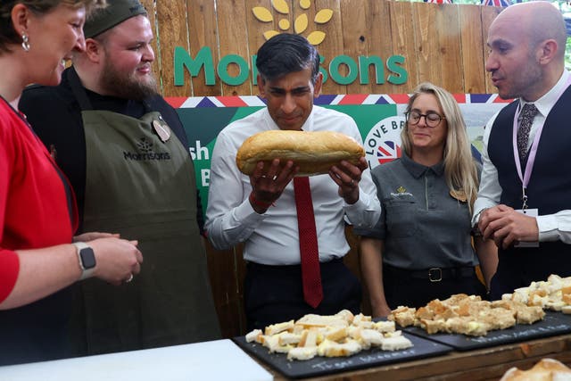 Prime Minister Rishi Sunak holds a loaf of bread in front of an obscured Morrisons logo during the second farm to fork summit on May 14 (Toby Melville/PA)