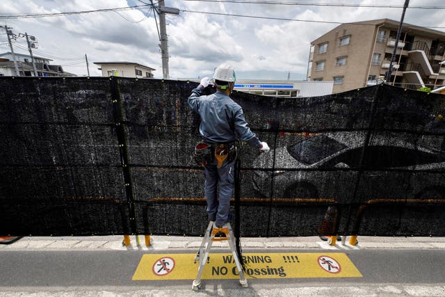 <p>A worker installs a barrier to block the sight of Japan’s Mount Fuji emerging from behind a convenience store to deter badly behaved tourists, in the town of Fujikawaguchiko, Yamanashi prefecture</p>