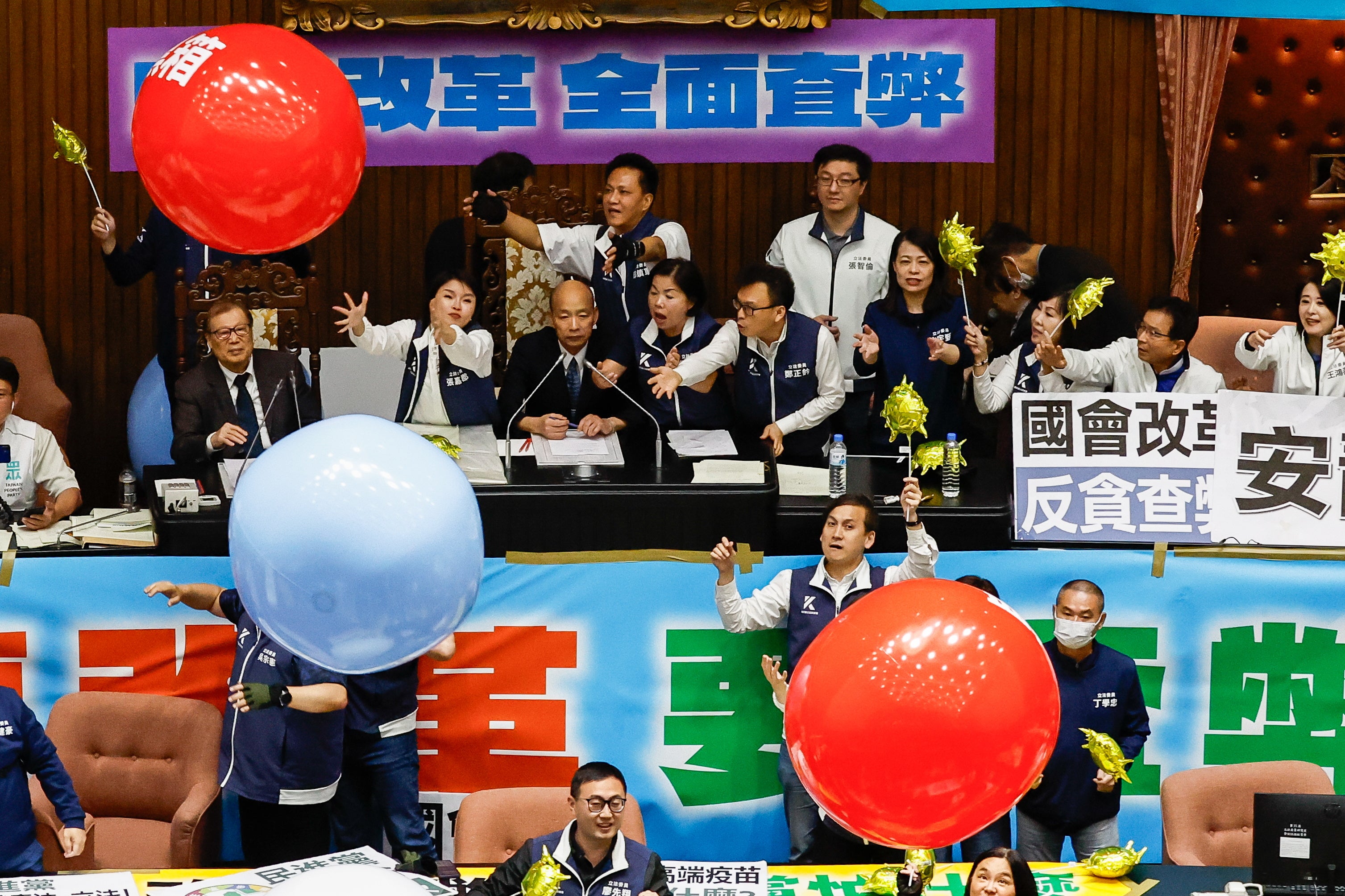 Taiwanese lawmakers from the Democratic Progressive Party throw inflatable balloons with words reading 'anti evil laws' at the Parliament President Han Kuo-yu