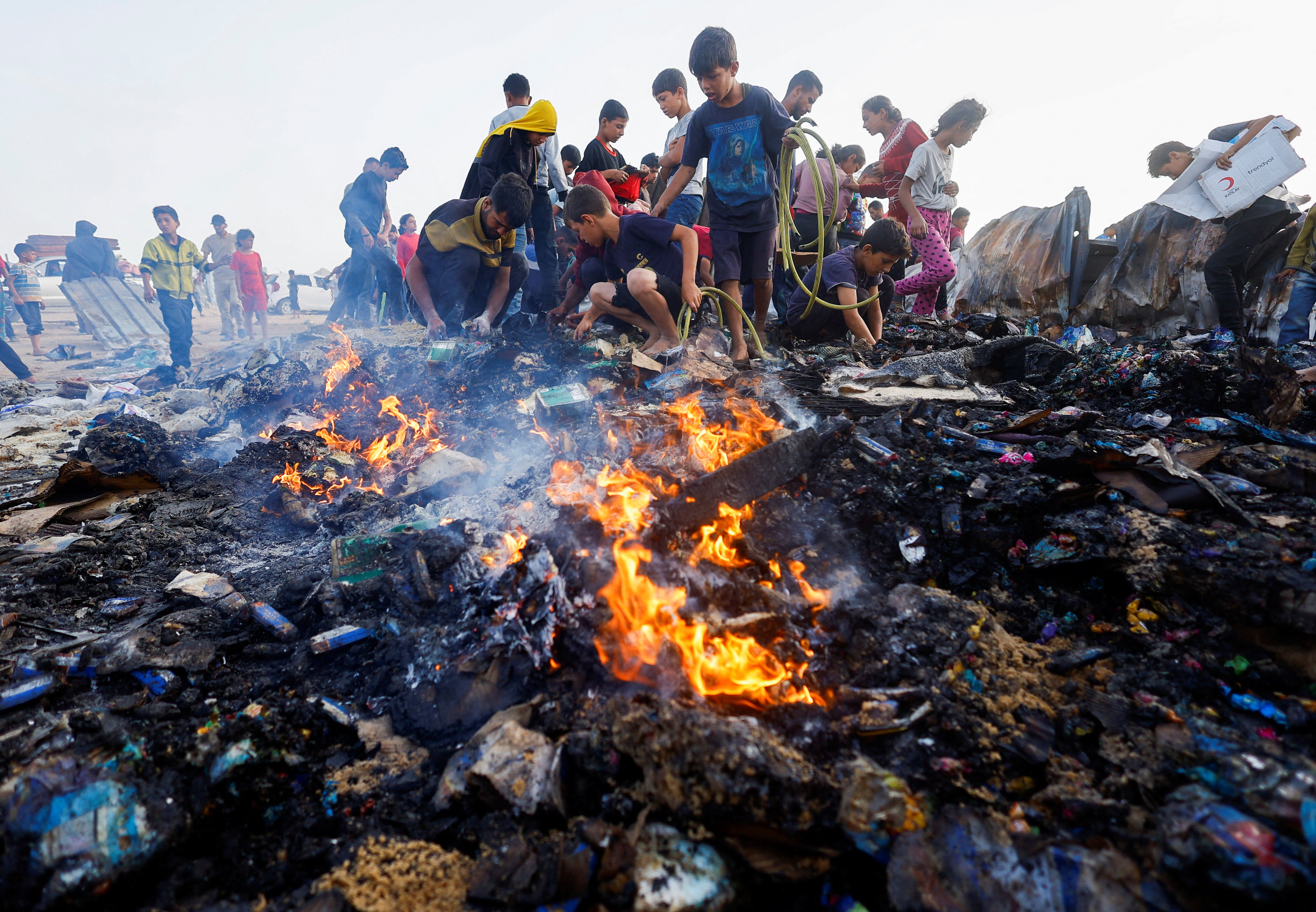Palestinians search for food among burnt debris in the aftermath of an Israeli strike on Rafah