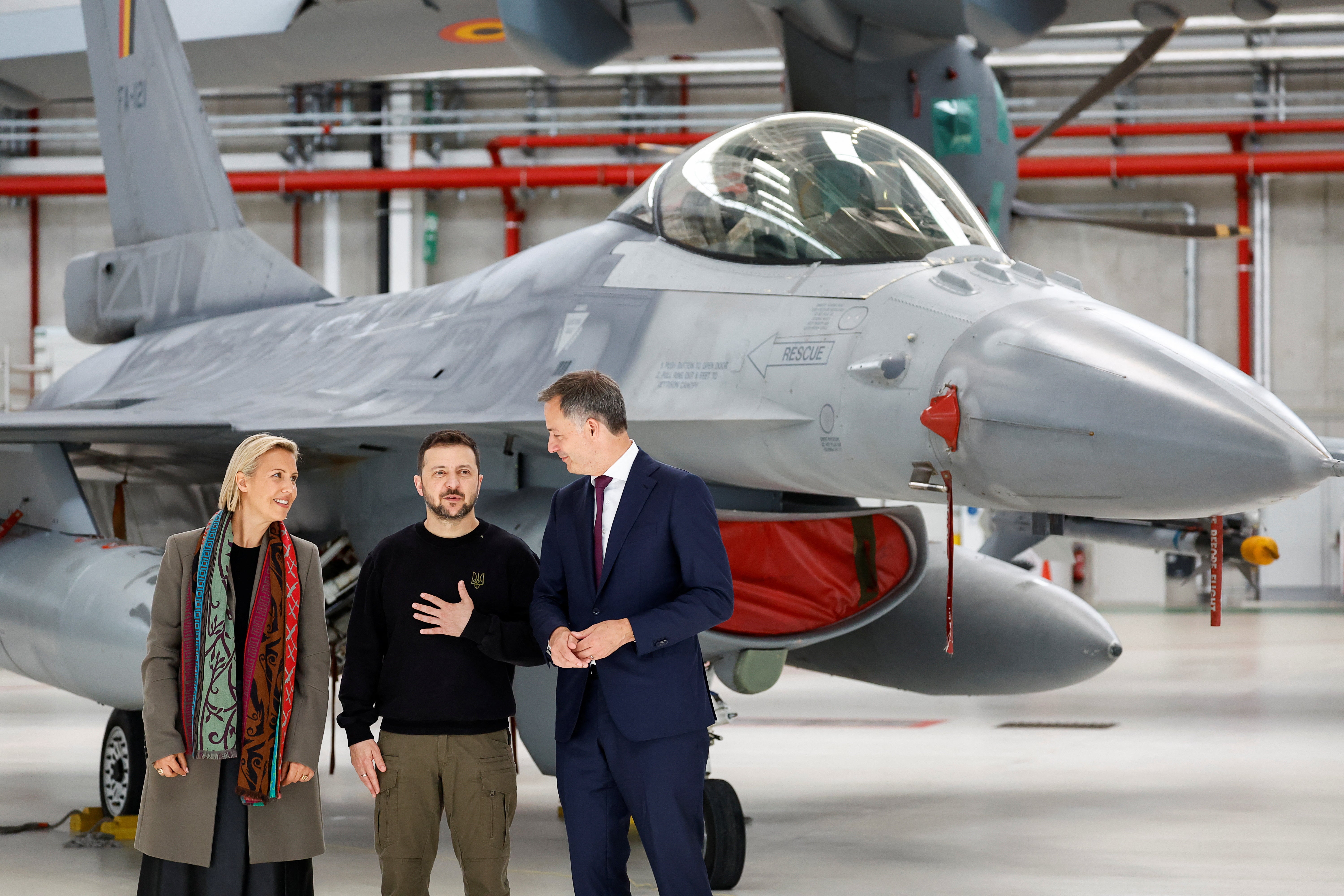 Ukraine's President Volodymyr Zelensky, Belgium's Prime Minister Alexander De Croo and Belgium's Defense Ludivine Dedonder stand near a F-16