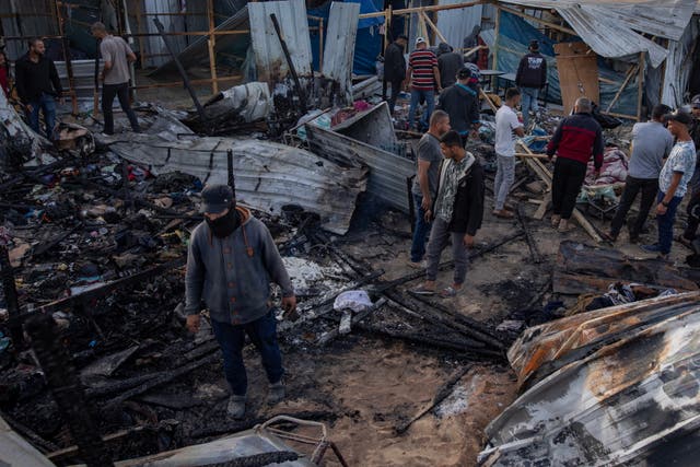 <p>Palestinians inspect the damage after an Israeli army raid on a camp at an area designated for displaced people in Rafah, southern Gaza Strip, 27 May 2024. </p>