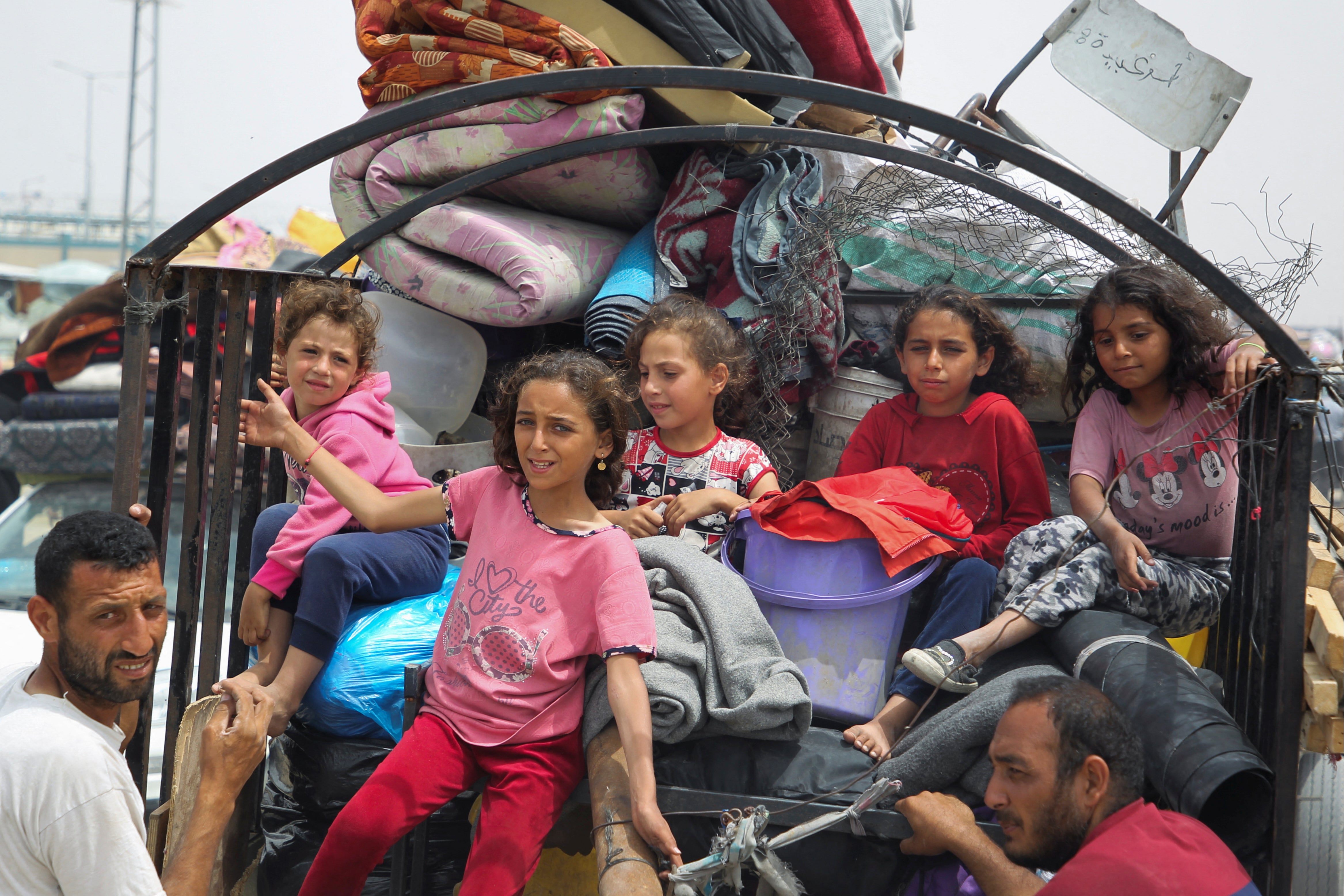 Children look on, as Palestinians travel on foot along with their belongings to flee Rafah
