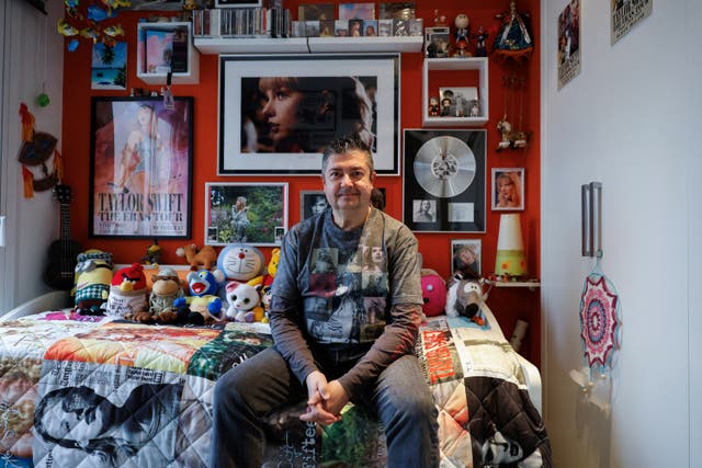 <p>Roberto Santos, 55, a Spanish superfan who is part of a select list of fans who receives exclusive gifts from the pop icon, poses in his ‘Taylor Swift shrine' in his home in Madrid, Spain</p>