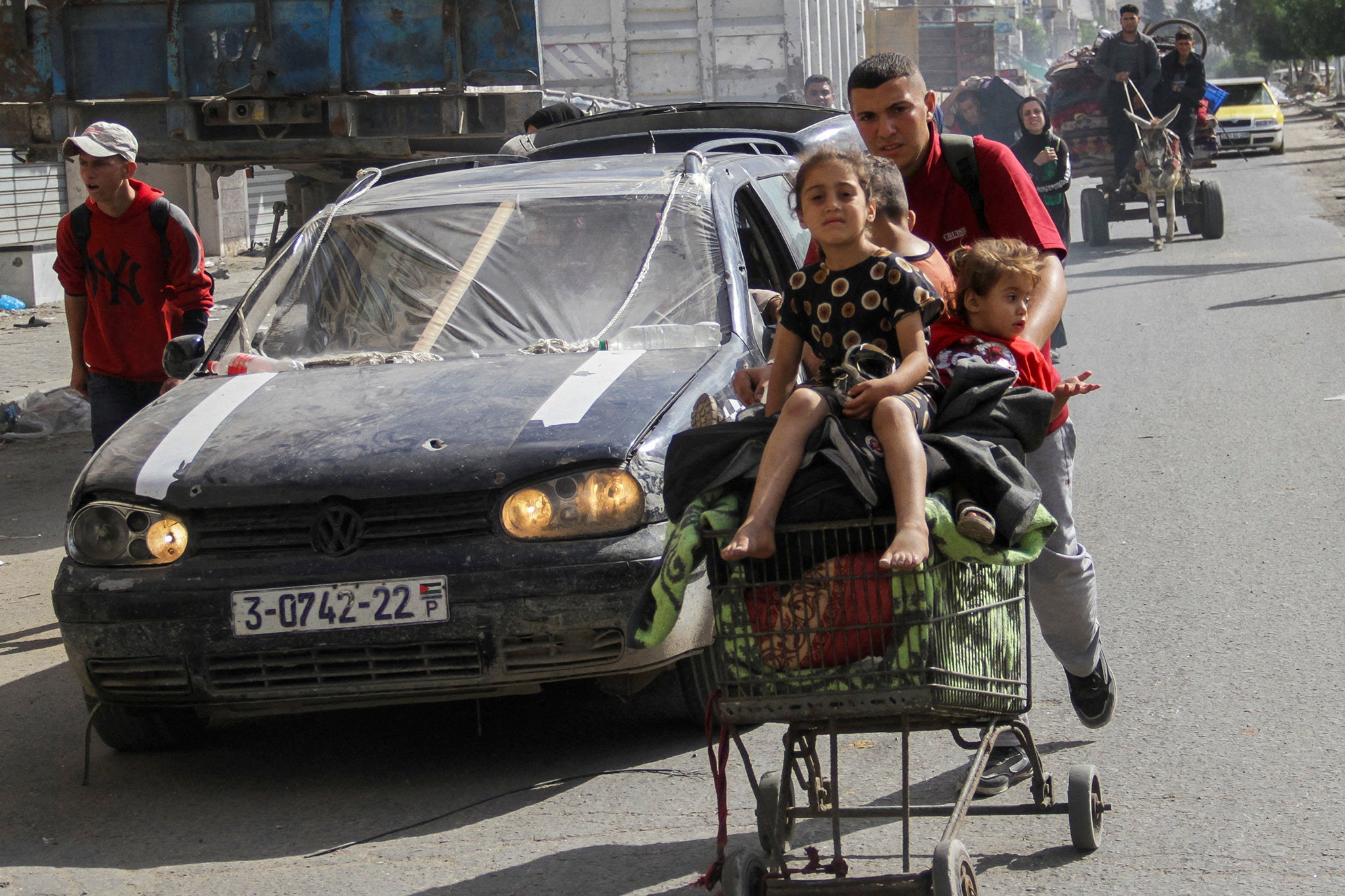 A displaced Palestinian man pushes children in a trolley as they make their way towards Gaza City after fleeing their home in northern Gaza