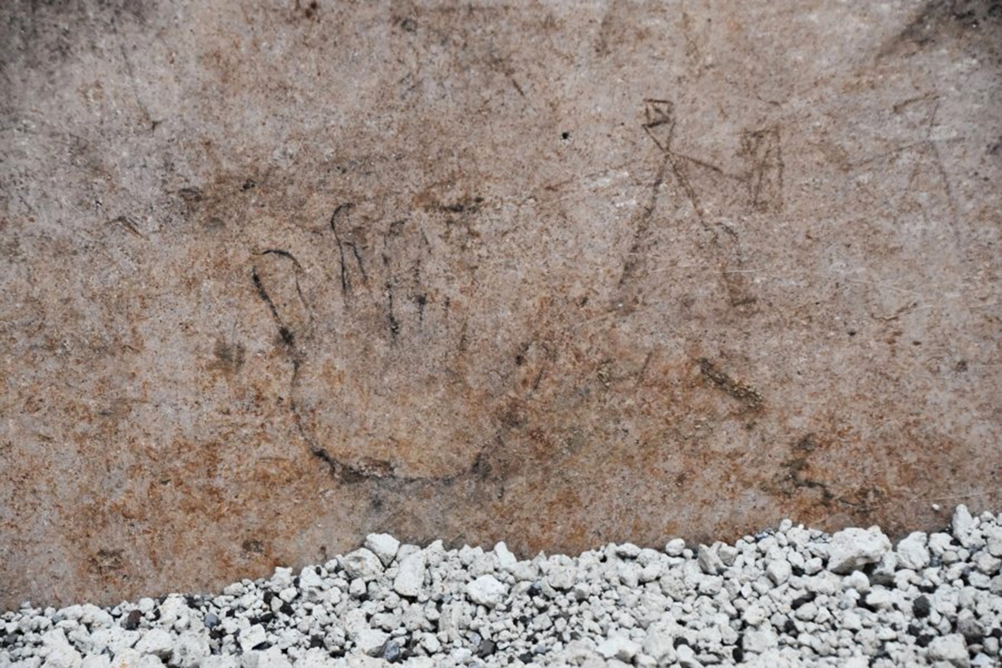 Cave drawing of a small hand (left) and human figures (right) uncovered in Pompeii