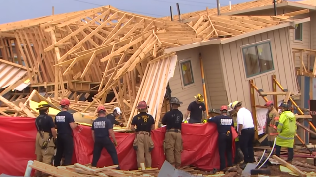 <p>Rescue crews stand outside a collapsed home in Magnolia County, Texas on Tuesday</p>