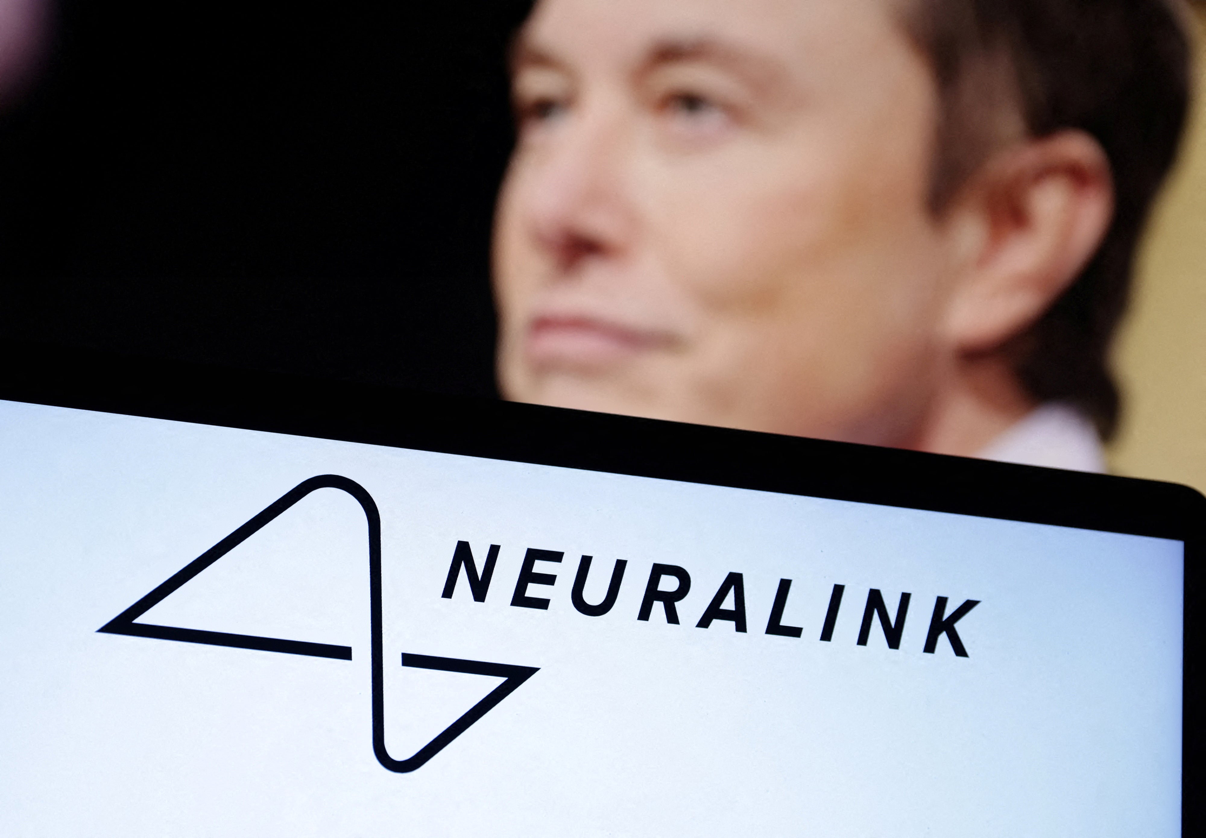 Elon Musk, and the Neuralink logo, pictured in 2022. A former Neuralink employee is suing the company, claiming she was fired after she told her superiors she was pregnant