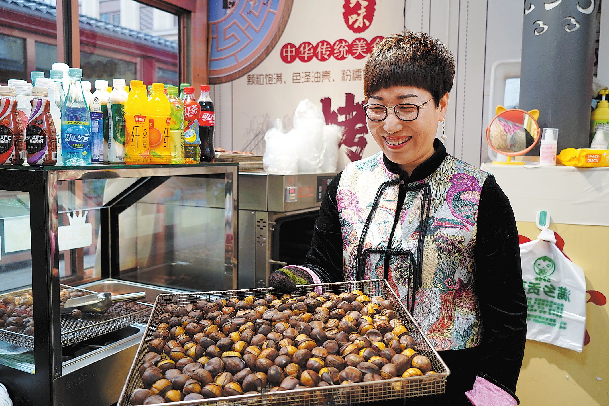 Food entrepreneur Liu Jianxia holds a tray of oven-roasted chestnuts at her shop in Chengde, Hebei, in March