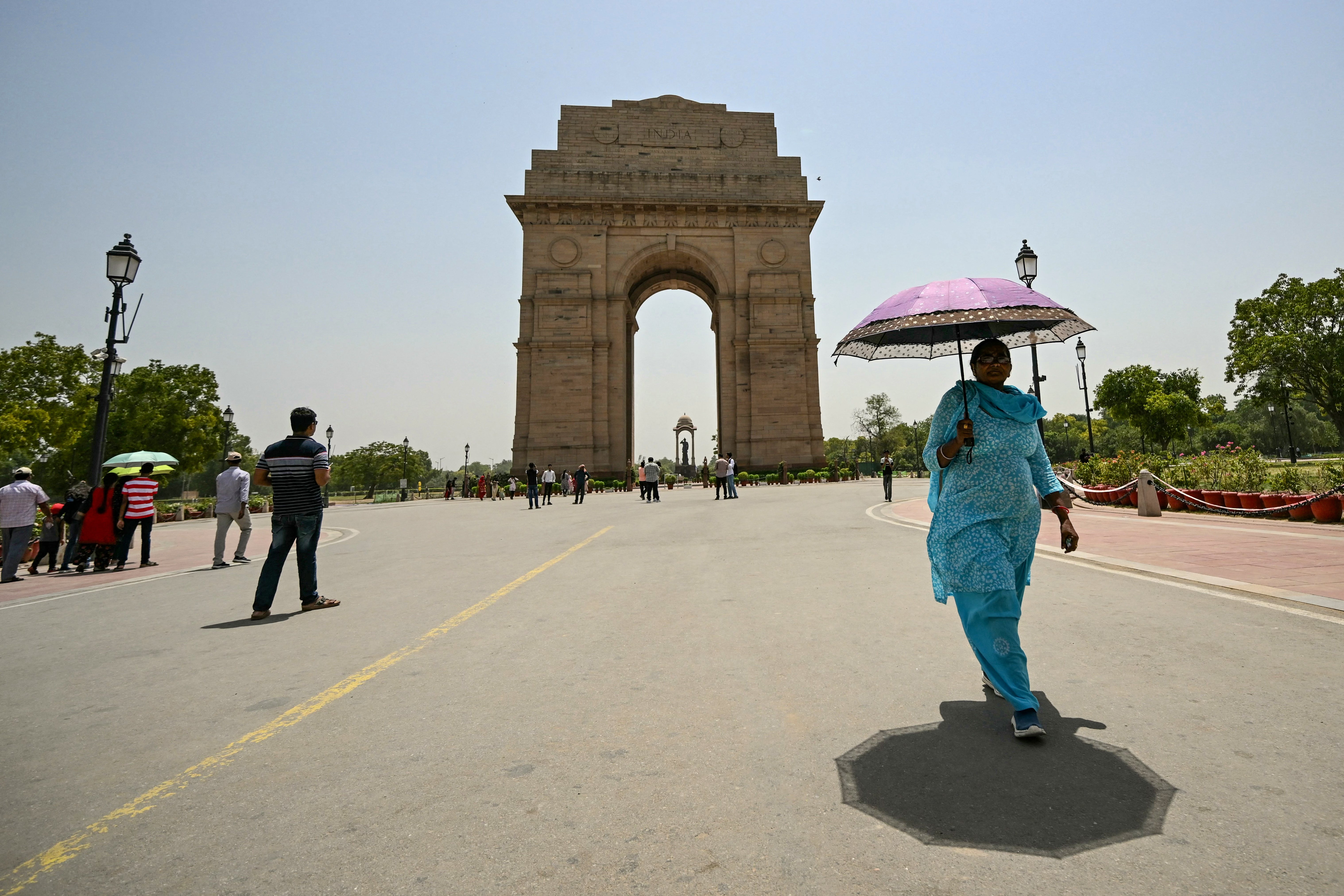 A woman holding an umbrella walks near the India Gate during severe heatwave on a hot summer day in Delhi